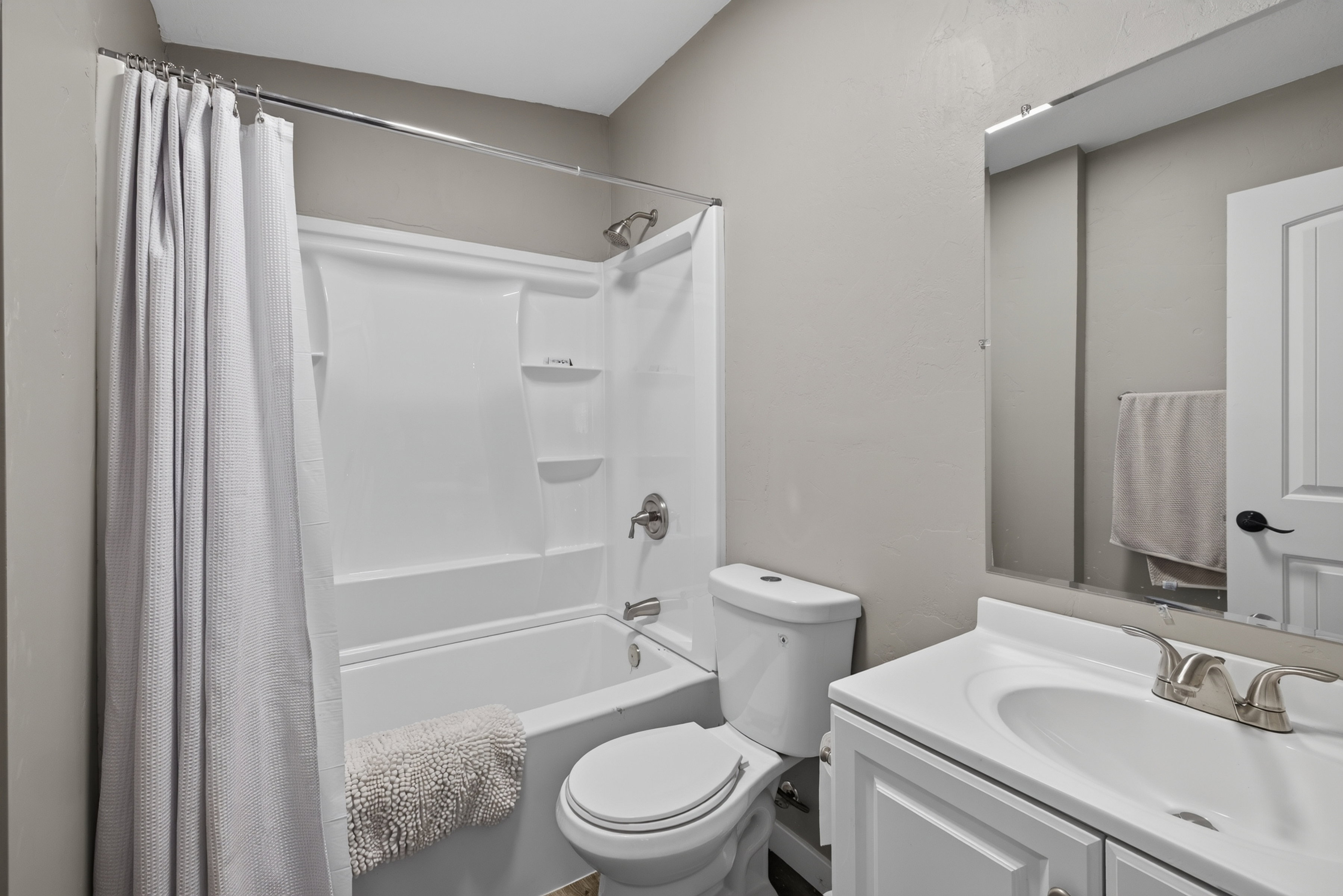 Bathroom featuring a white vanity with integrated sink, chrome faucet, and a large wall-mounted mirror