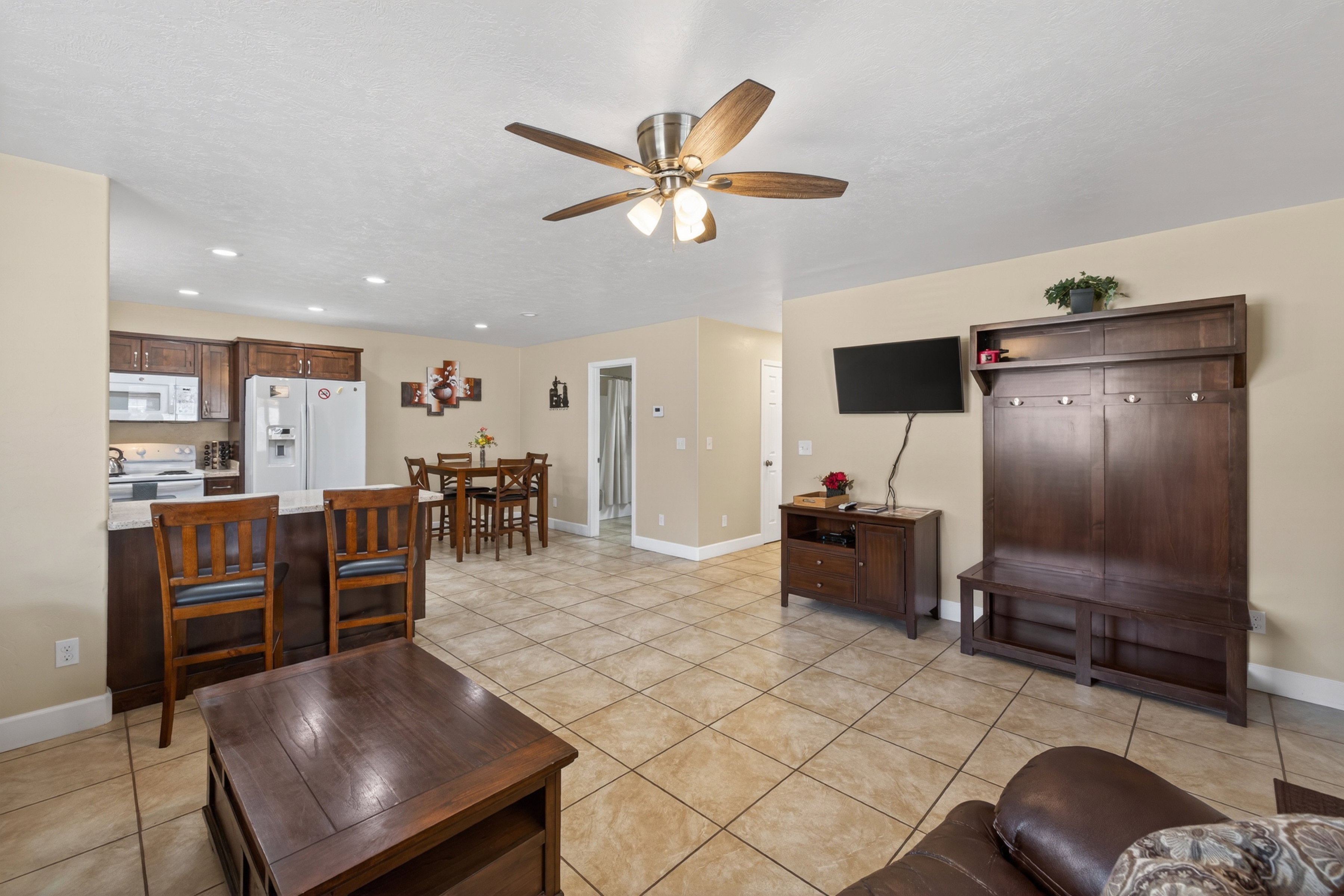 Open-concept living space featuring ceramic tile flooring, a kitchen with wood cabinetry and white appliances, and a dining area with a wood-finish table