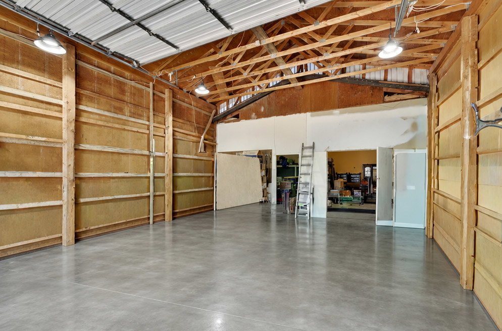 Spacious interior featuring a polished concrete floor, exposed wooden beam ceiling, and ample overhead lighting