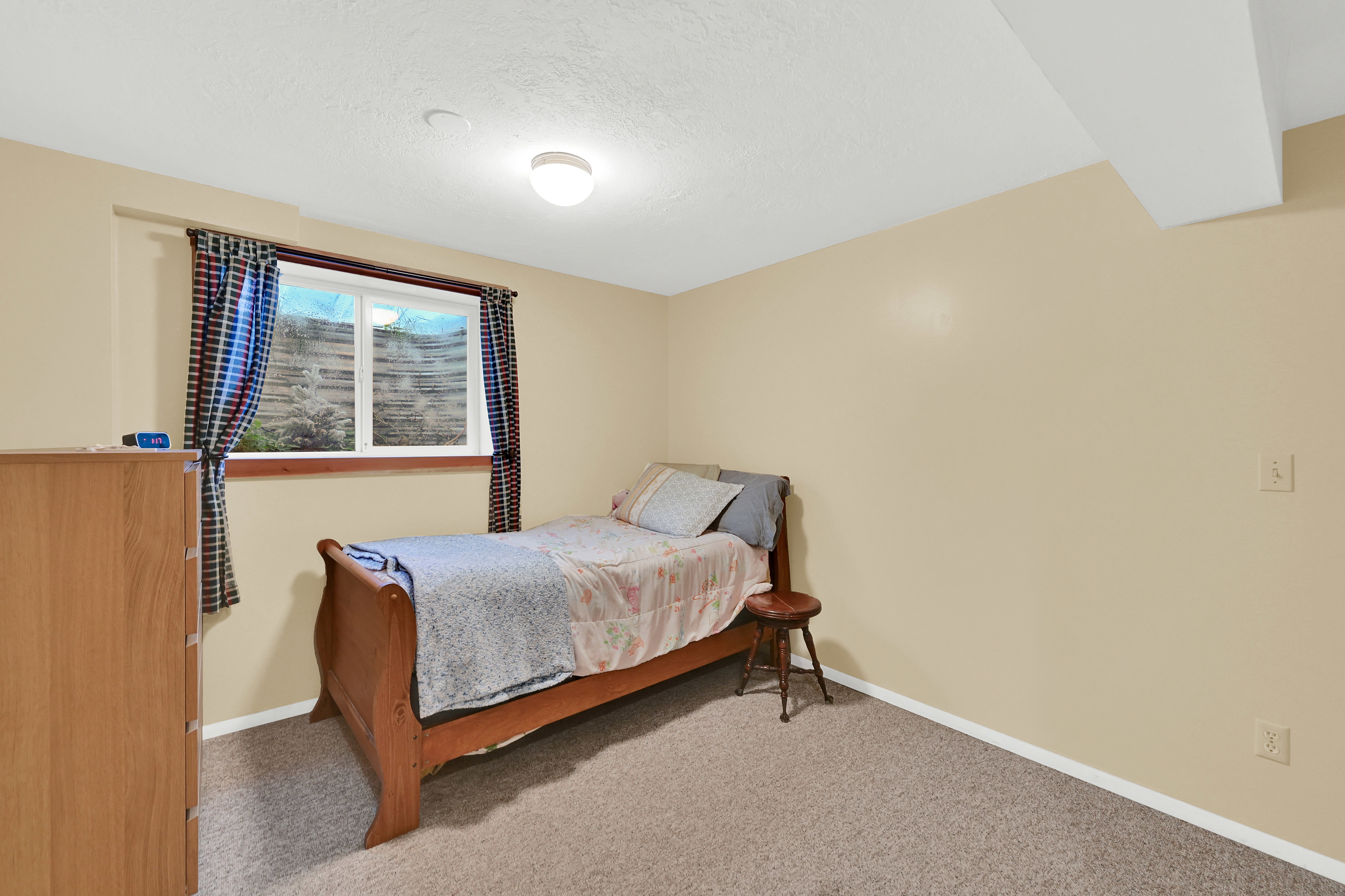 Carpeted room featuring a window with a wood trim, neutral wall color, and a ceiling-mounted light fixture