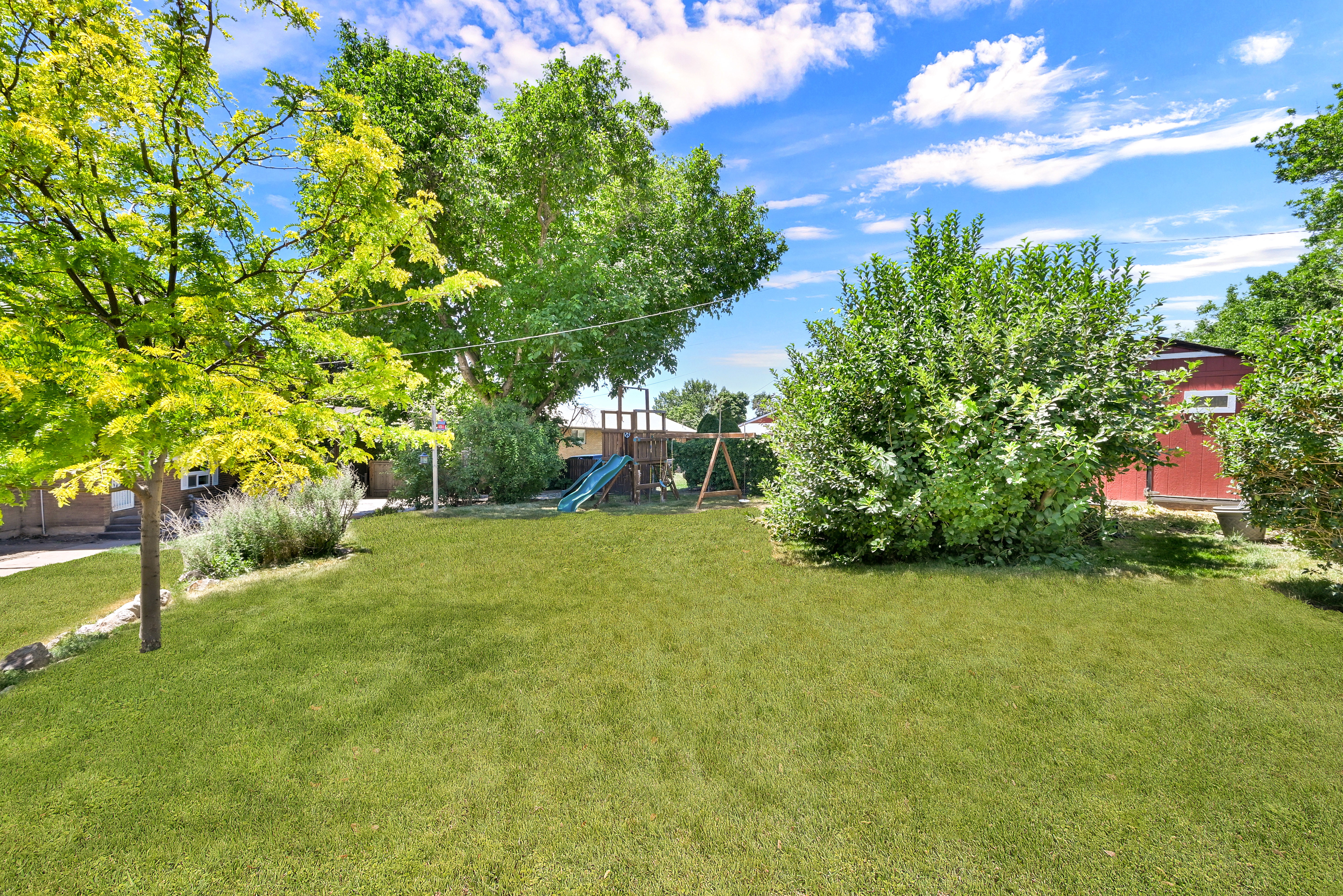 Spacious backyard featuring an expansive green lawn and mature trees