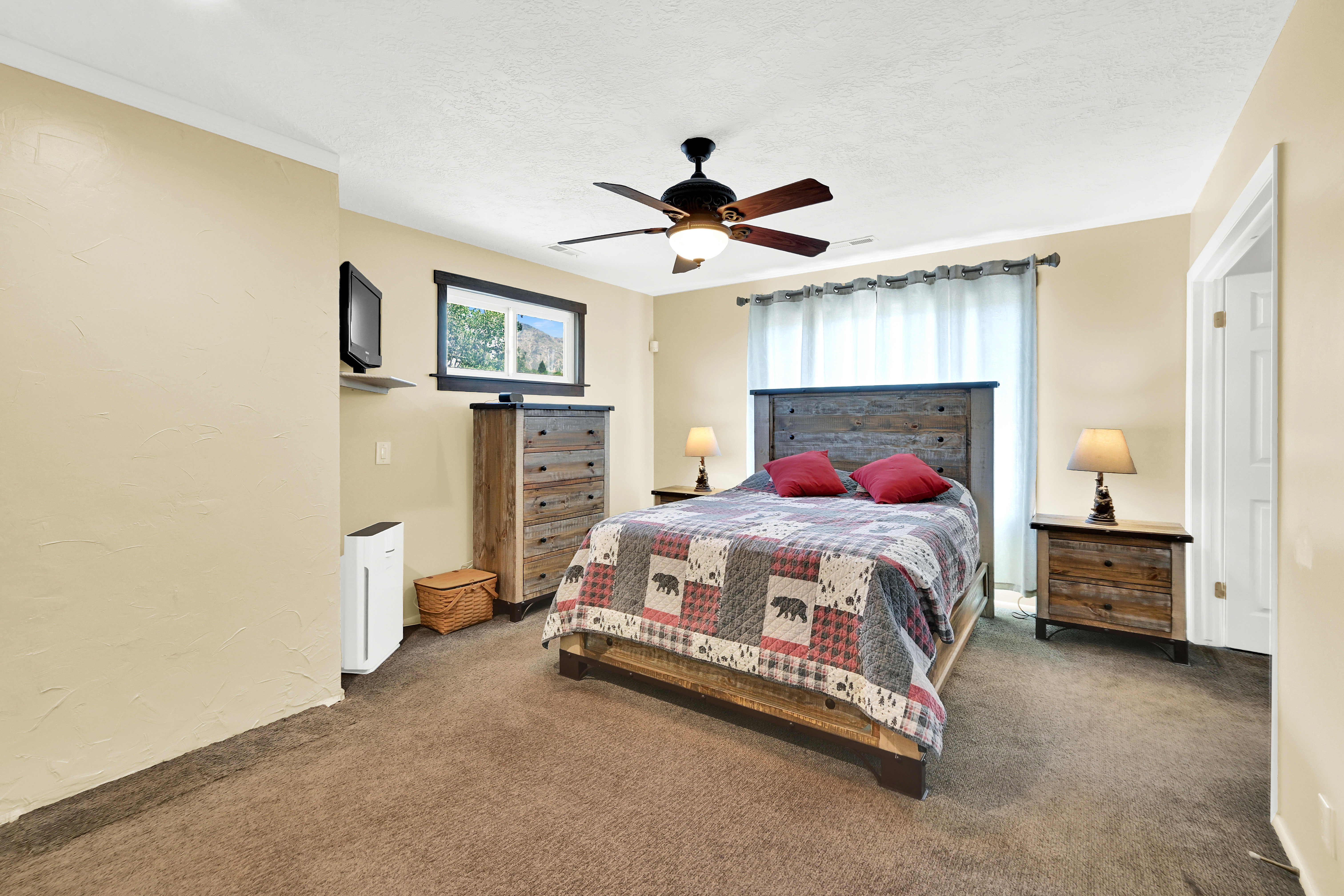 Carpeted room featuring a ceiling fan, a window with dark trim, and a doorway with a white door