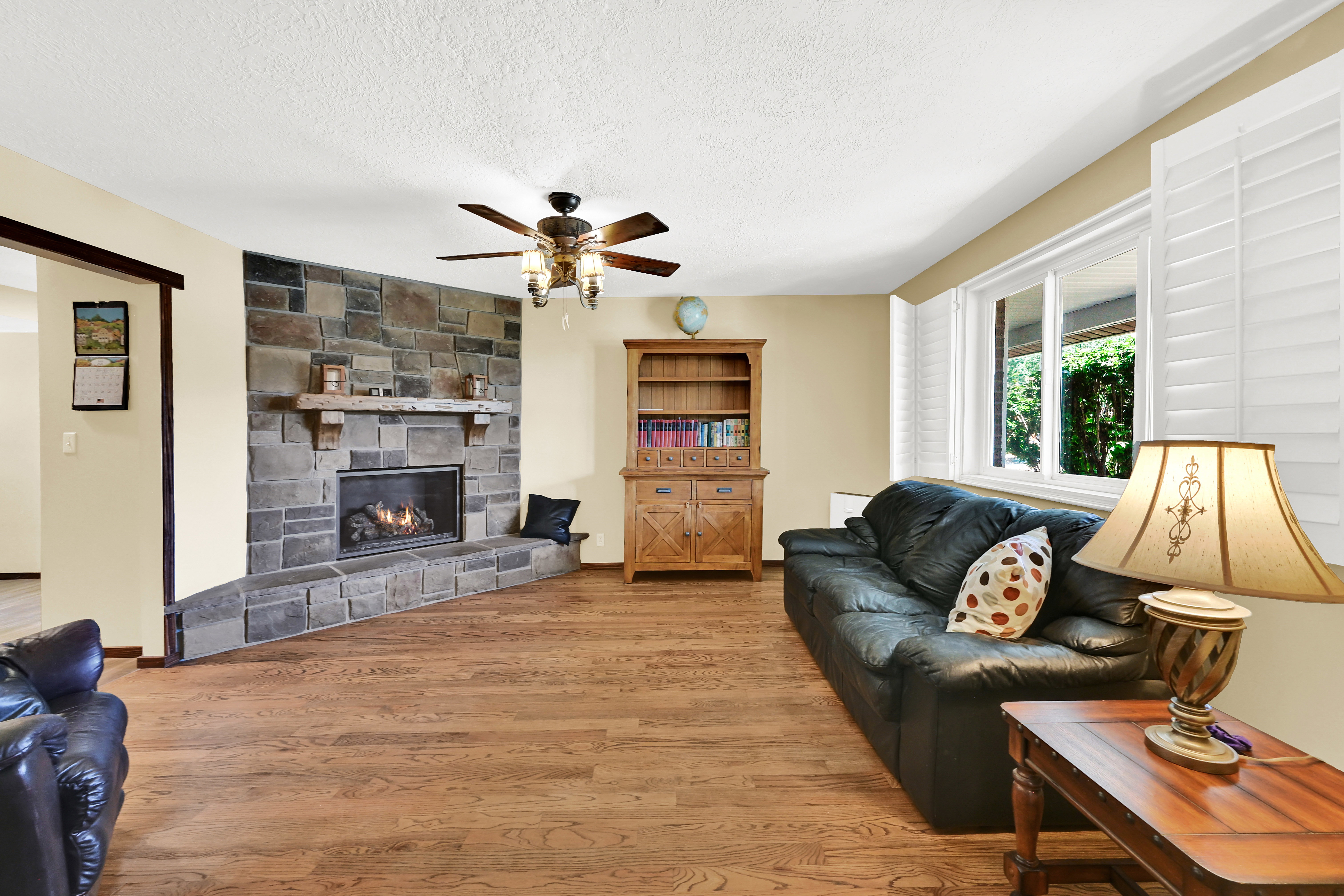 Living area featuring wood-finish flooring and a stone fireplace with a substantial mantel
