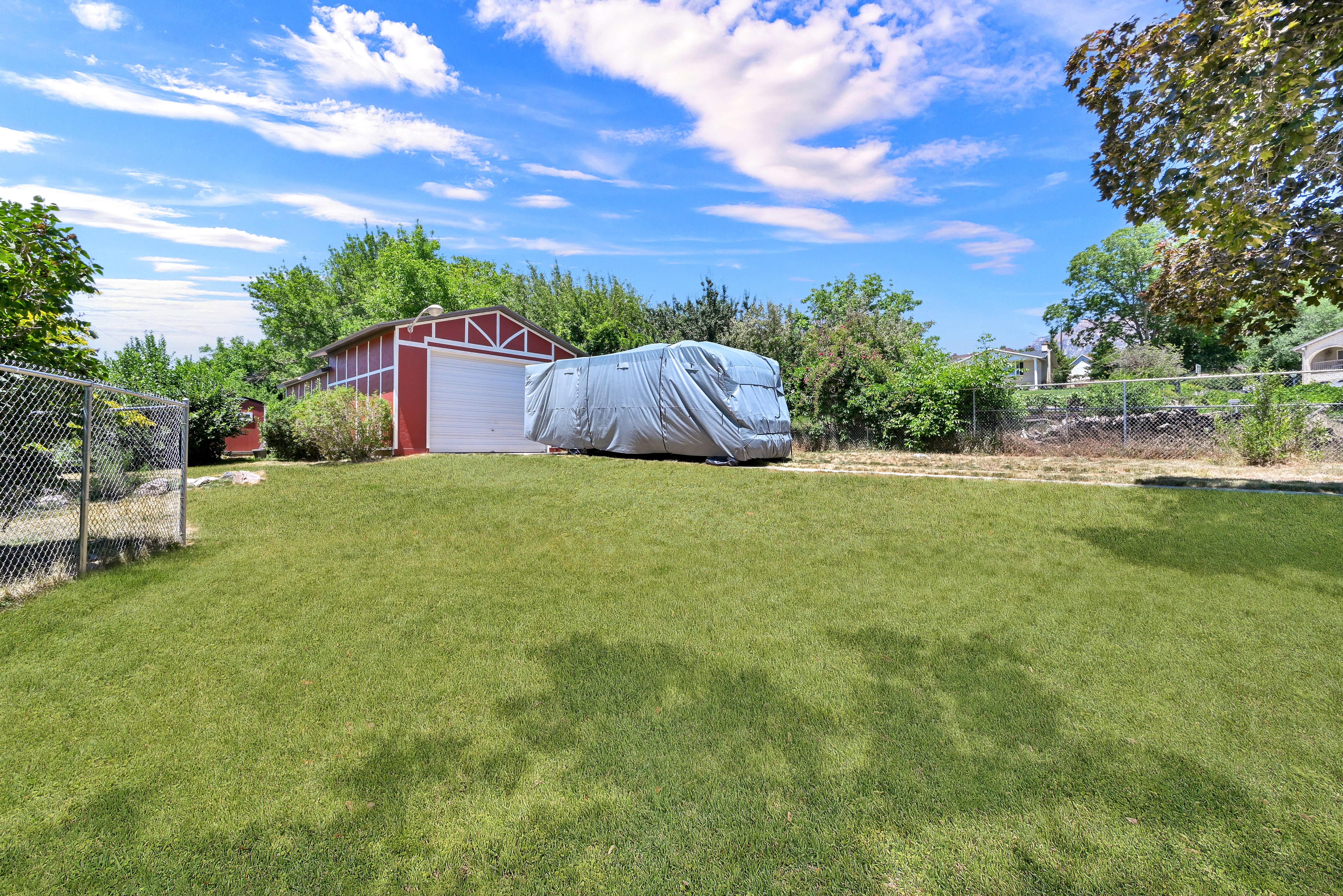 Spacious yard with a red barn-style auxiliary structure featuring a white garage door