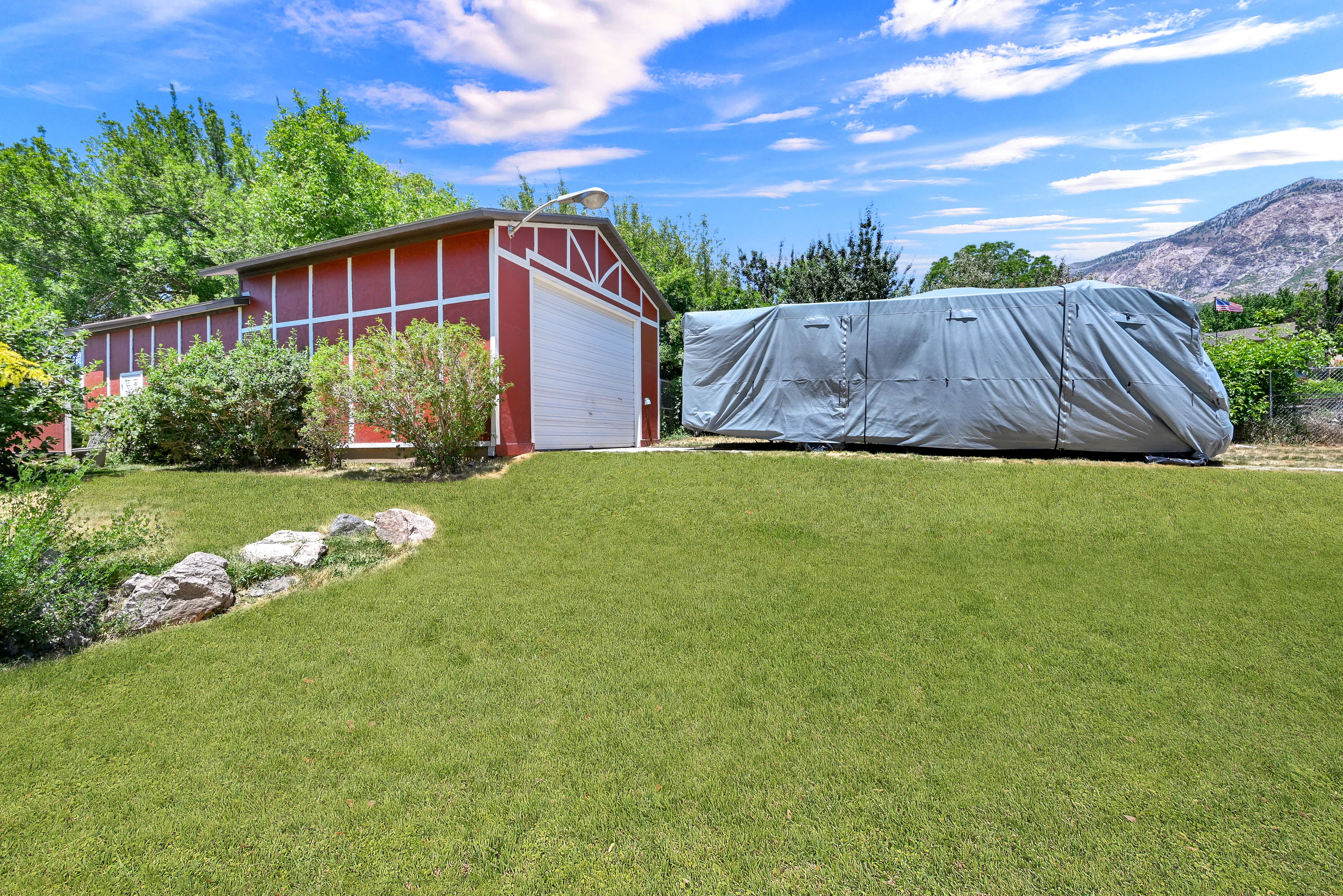 Red barn-style outbuilding with a white garage door, featuring a pitched roofline and exterior lighting