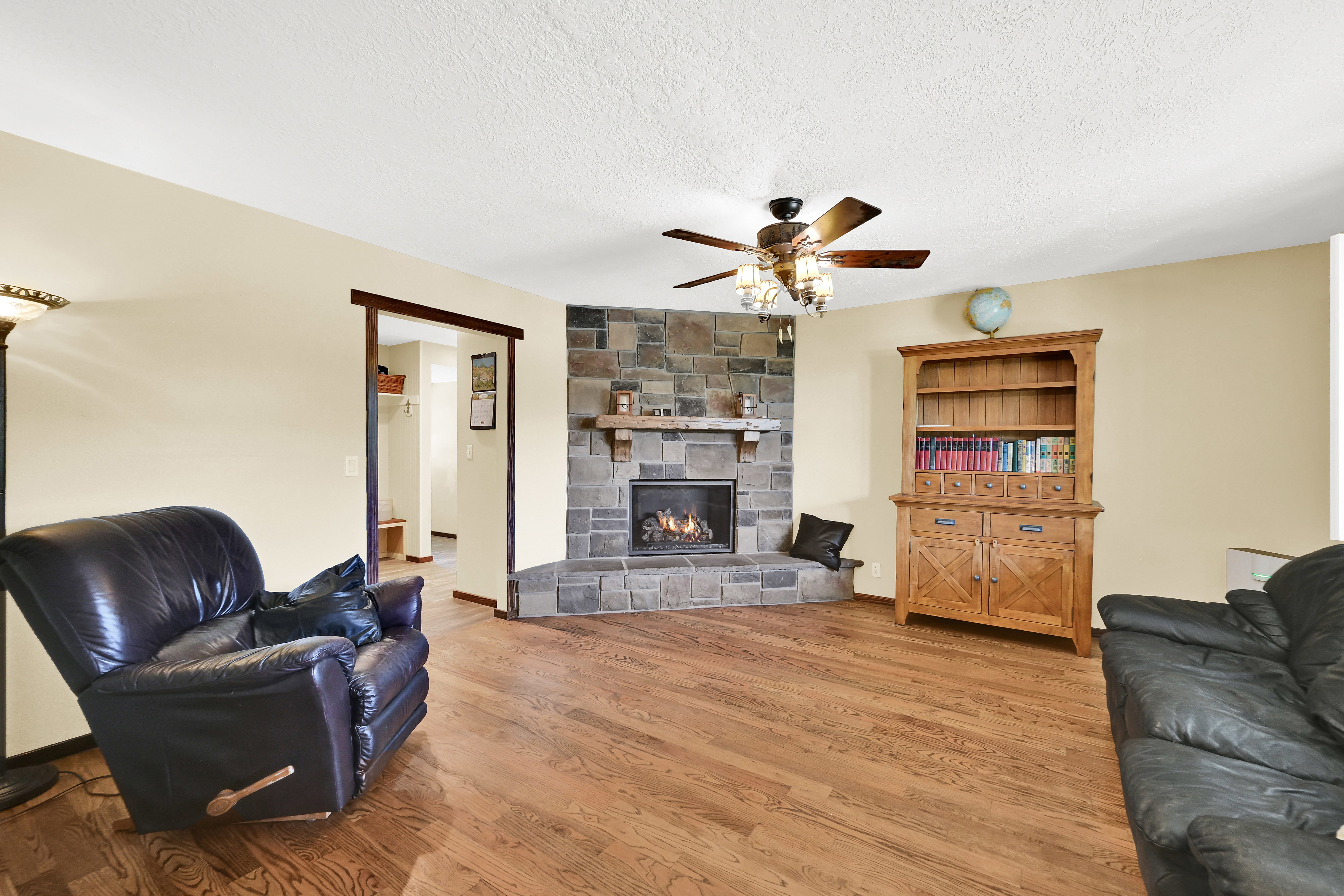 Living area featuring a corner stone-faced fireplace with a stone hearth and wood mantel