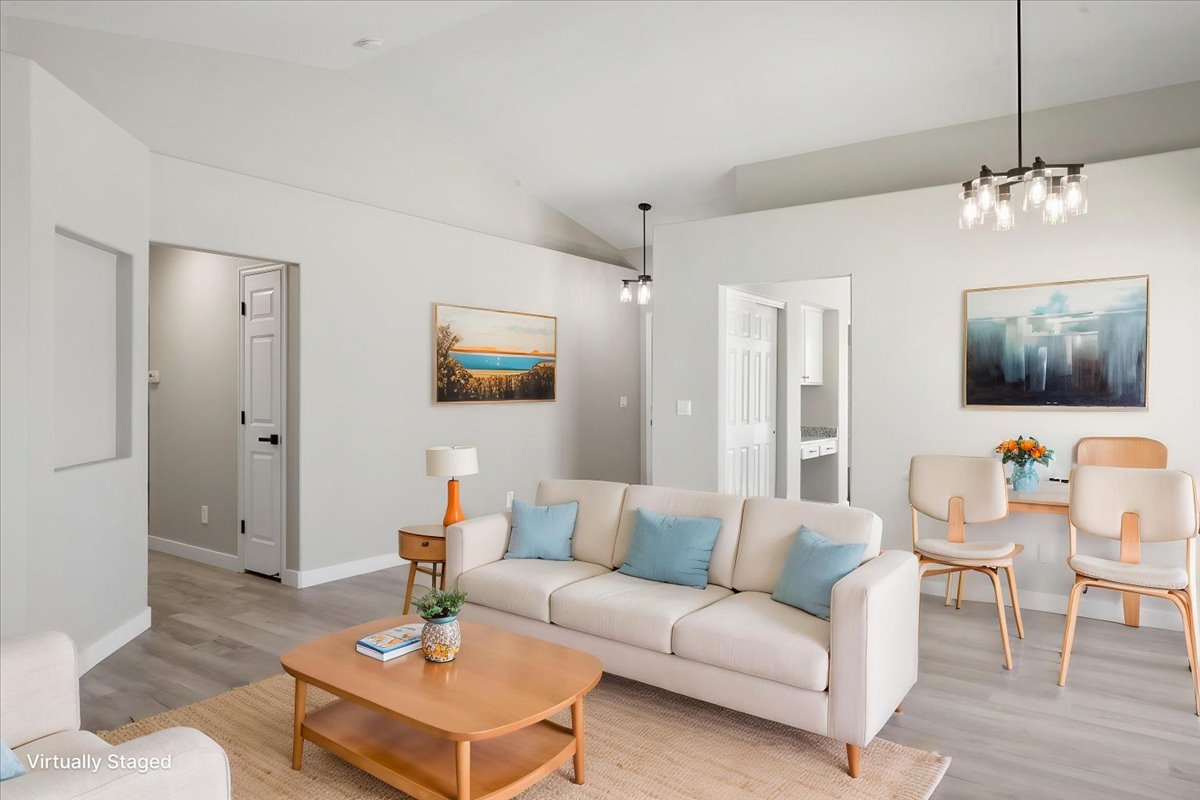 Spacious living area featuring vaulted ceilings, light wood-finish flooring, and recessed lighting