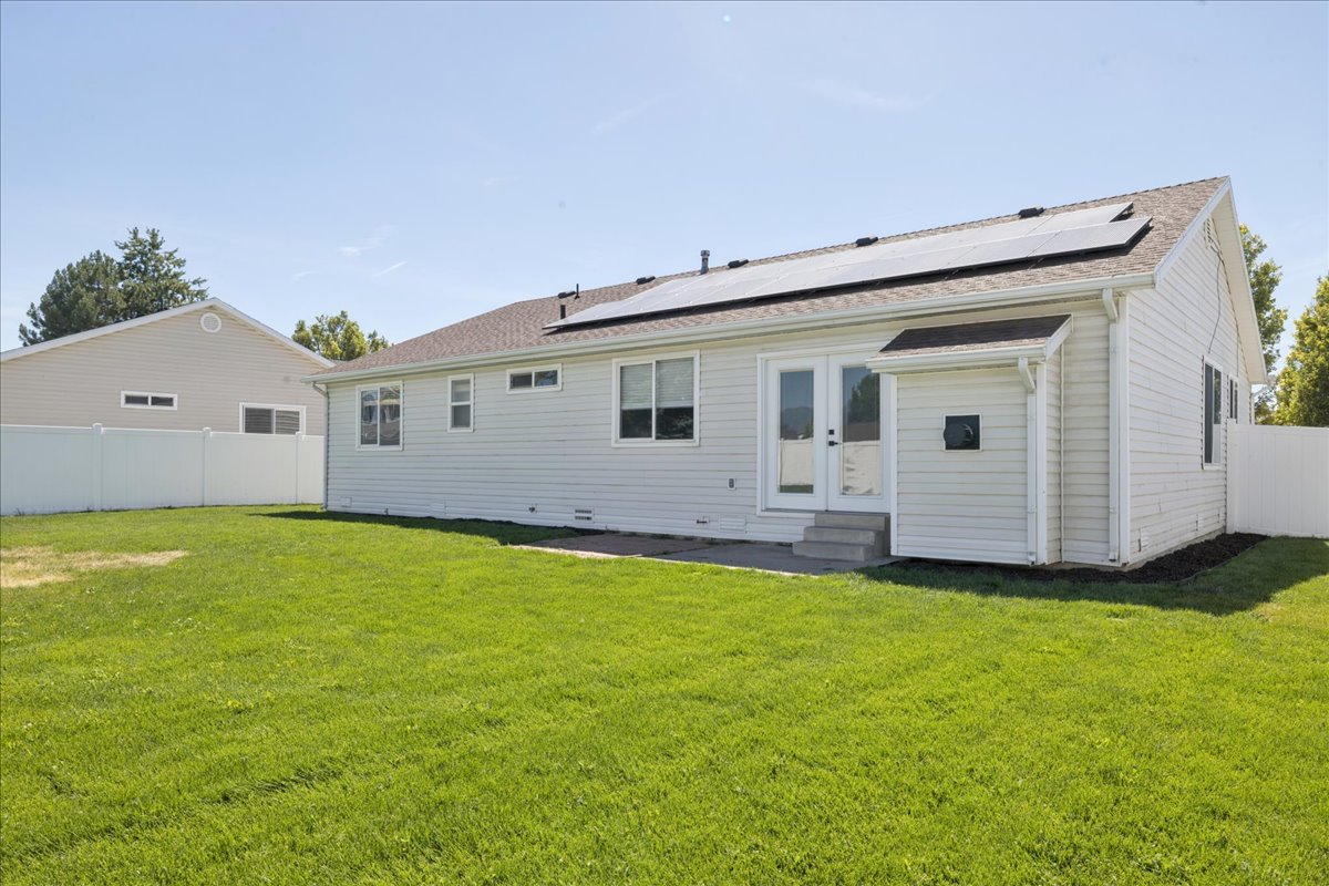 Expansive green lawn with a white vinyl fence and a white siding home