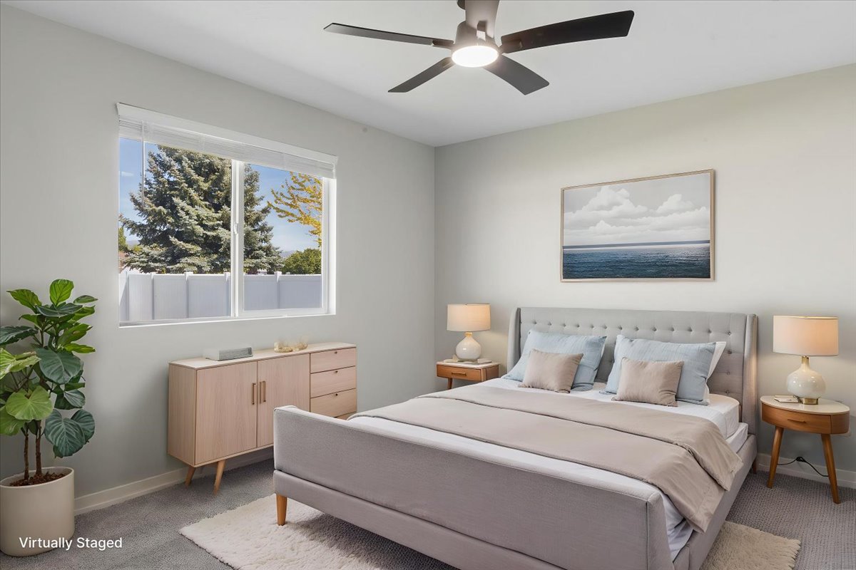Bright bedroom featuring carpet flooring, a large window with white blinds, and a ceiling fan with integrated lighting
