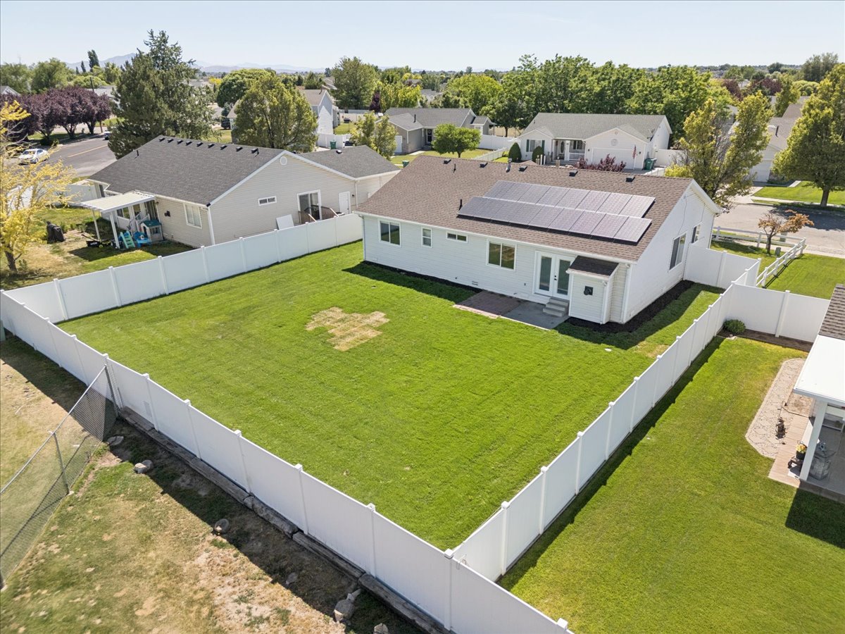 Expansive rear yard featuring a white privacy fence, green lawn, and a light-colored home with a dark-shingled roof