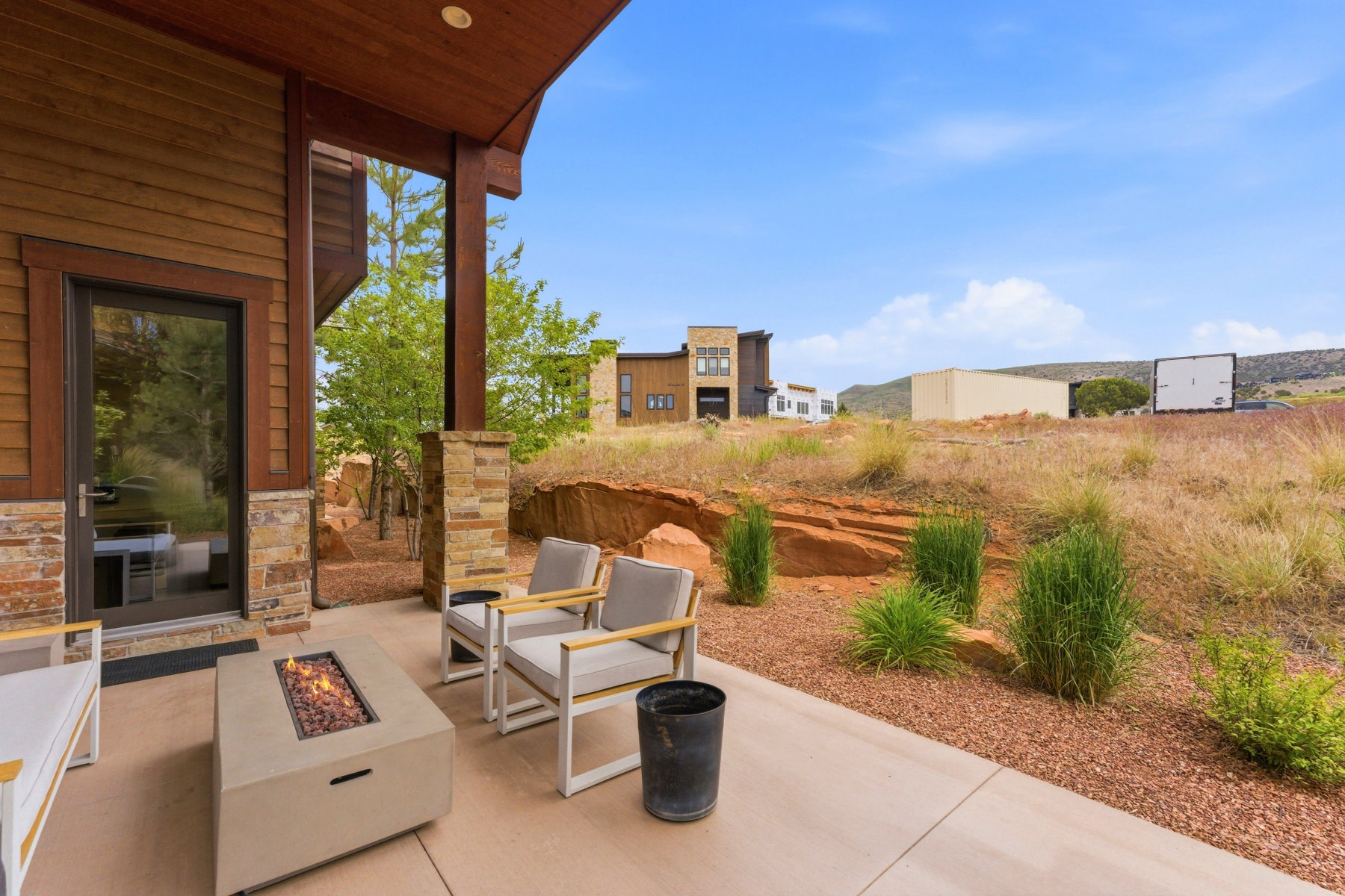 Covered patio featuring a concrete floor, integrated fire pit, and stone-clad columns