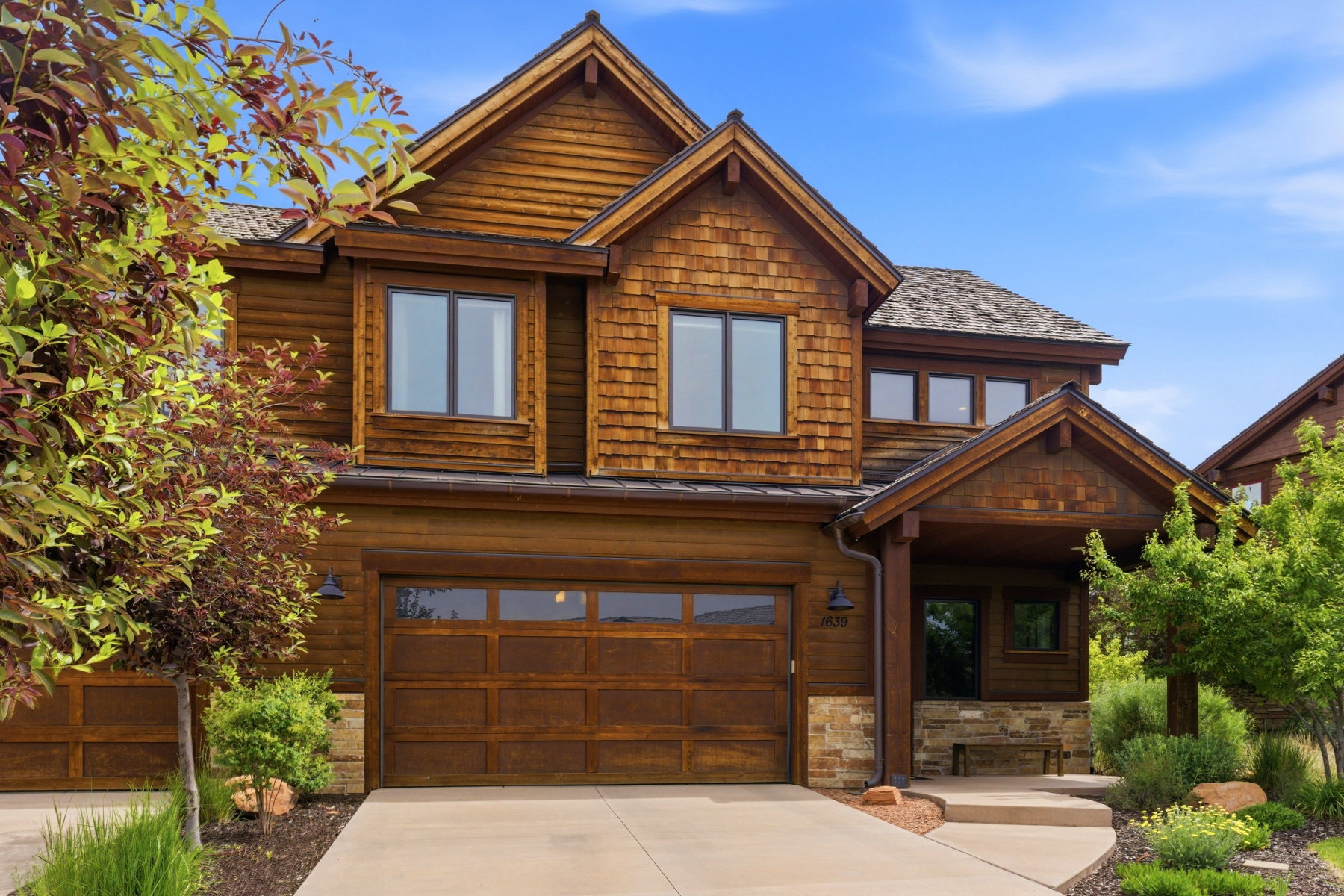 Craftsman-style facade featuring cedar shake siding, a covered front entry, and a two-car garage with wood-finish doors