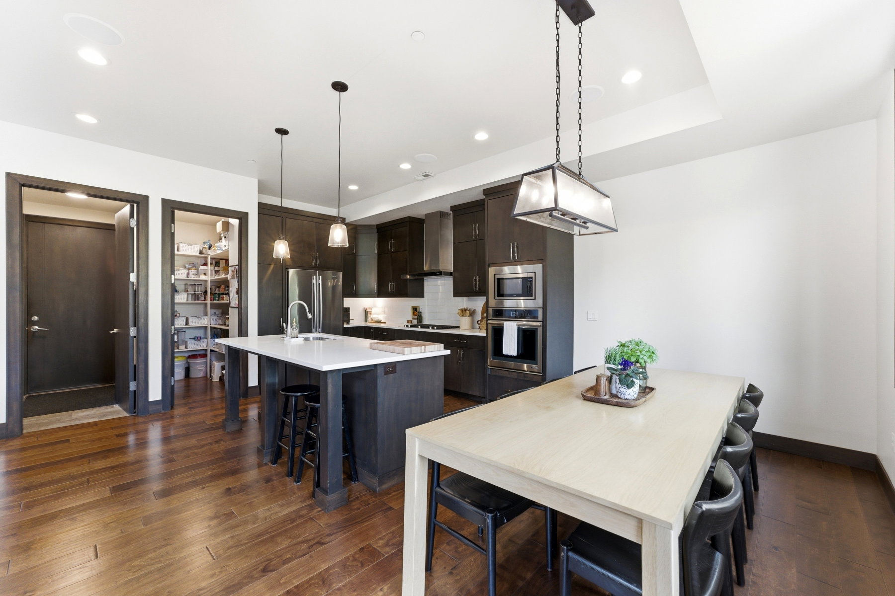 Modern kitchen featuring wood-finish flooring, dark cabinetry, and integrated stainless steel appliances