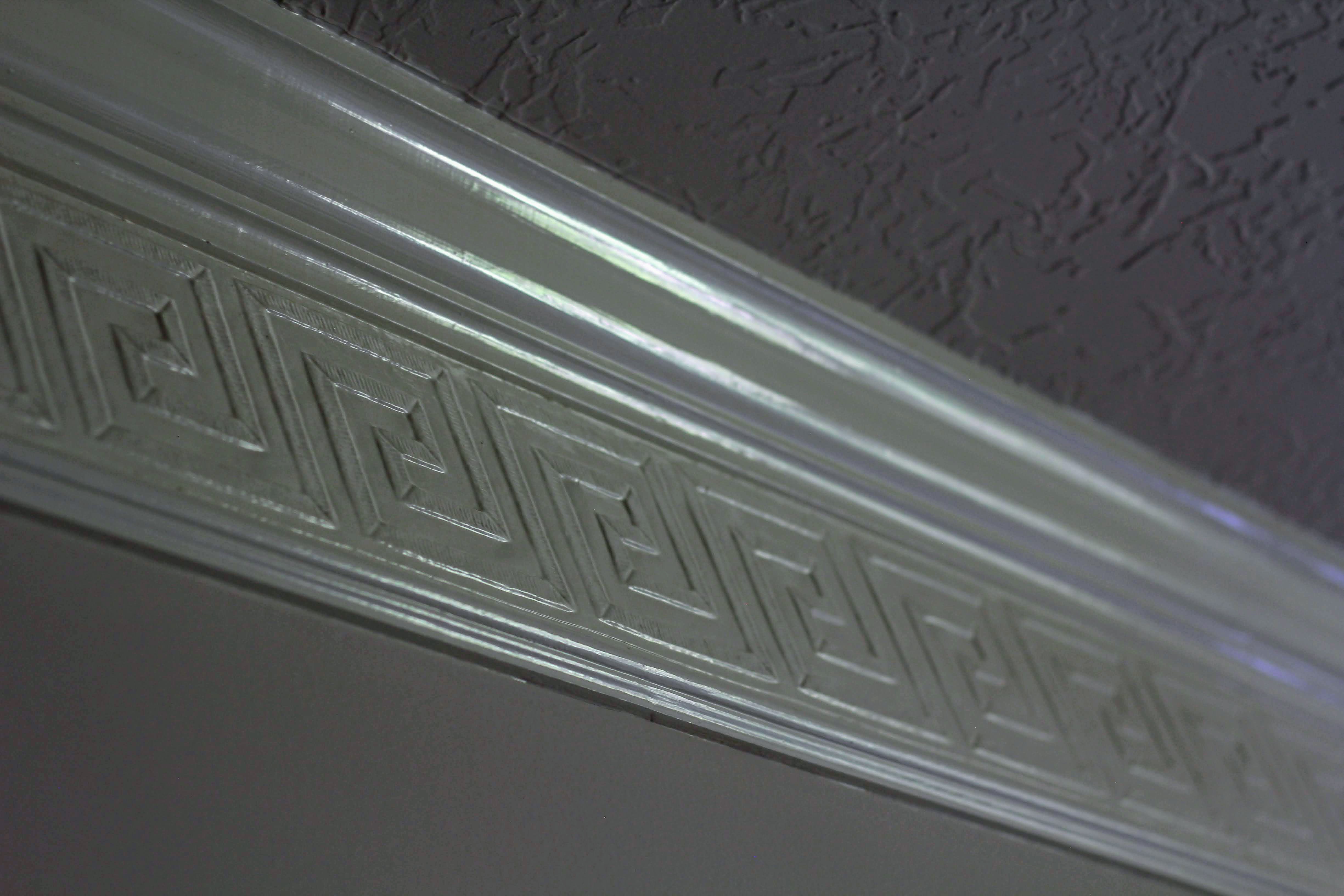 Crown molding with a Greek Key pattern, featuring a textured ceiling finish