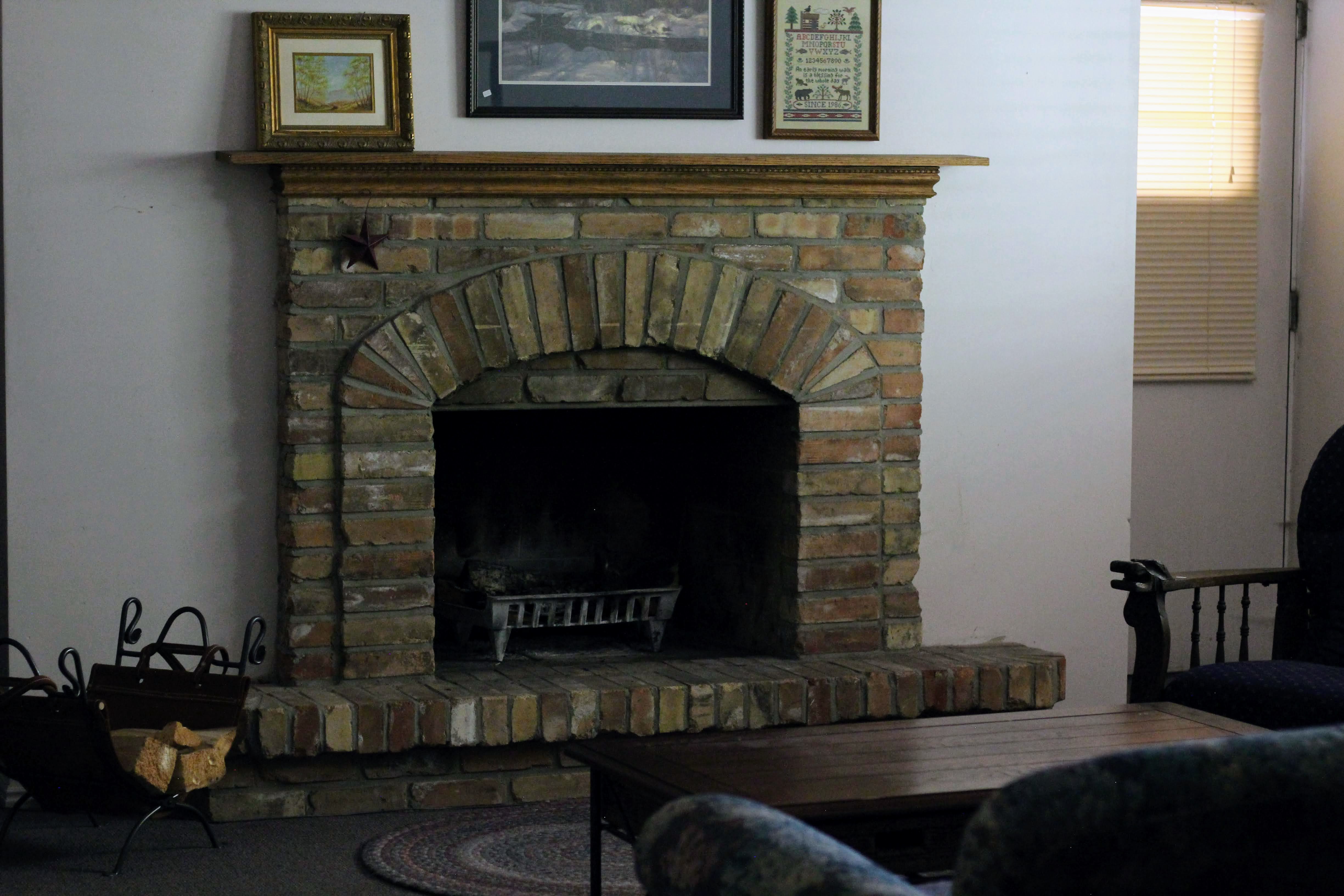 Brick fireplace featuring an arched firebox opening and a natural wood mantel