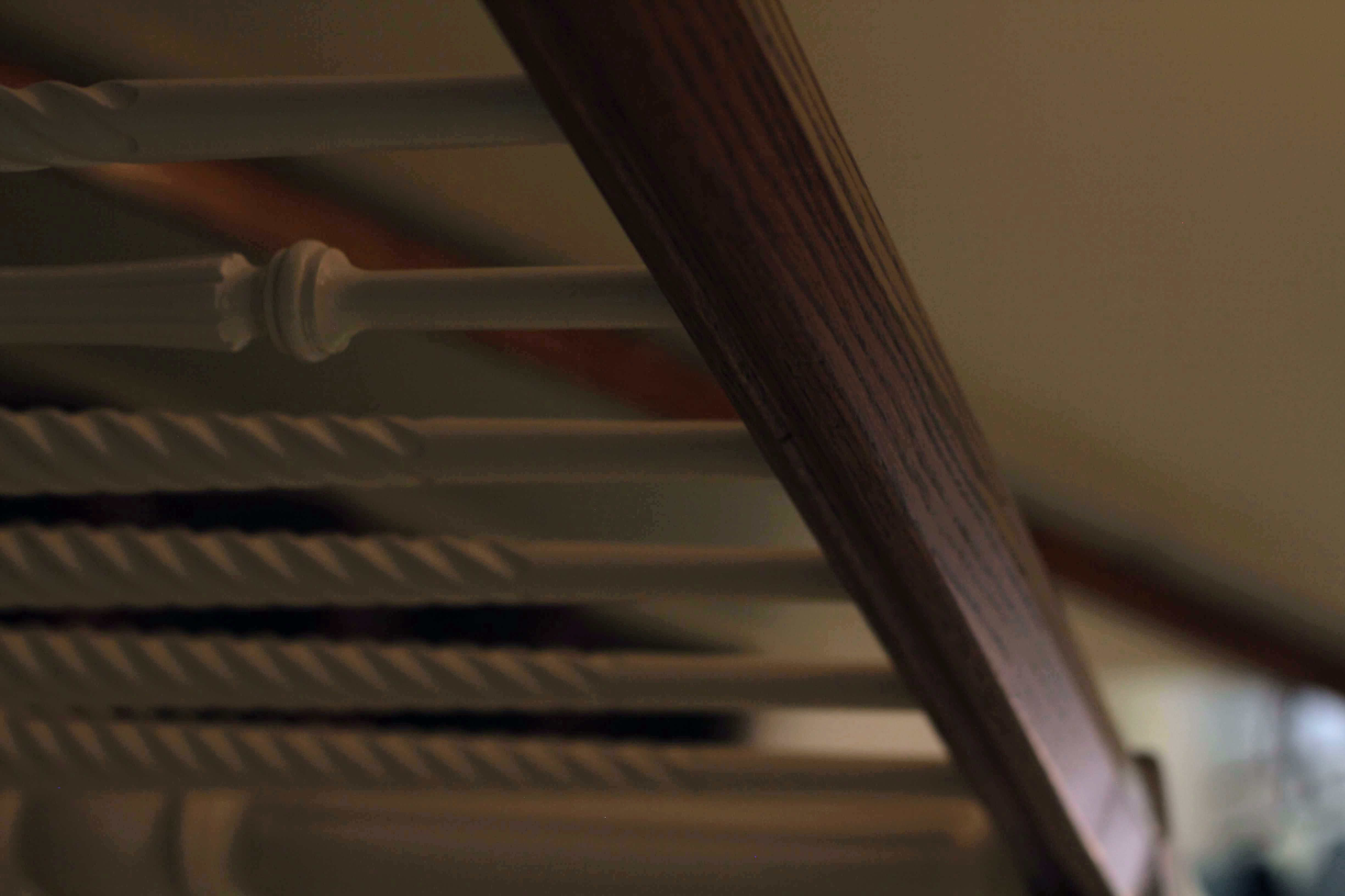 Wood-finish handrail with white painted balusters, some featuring a twisted design