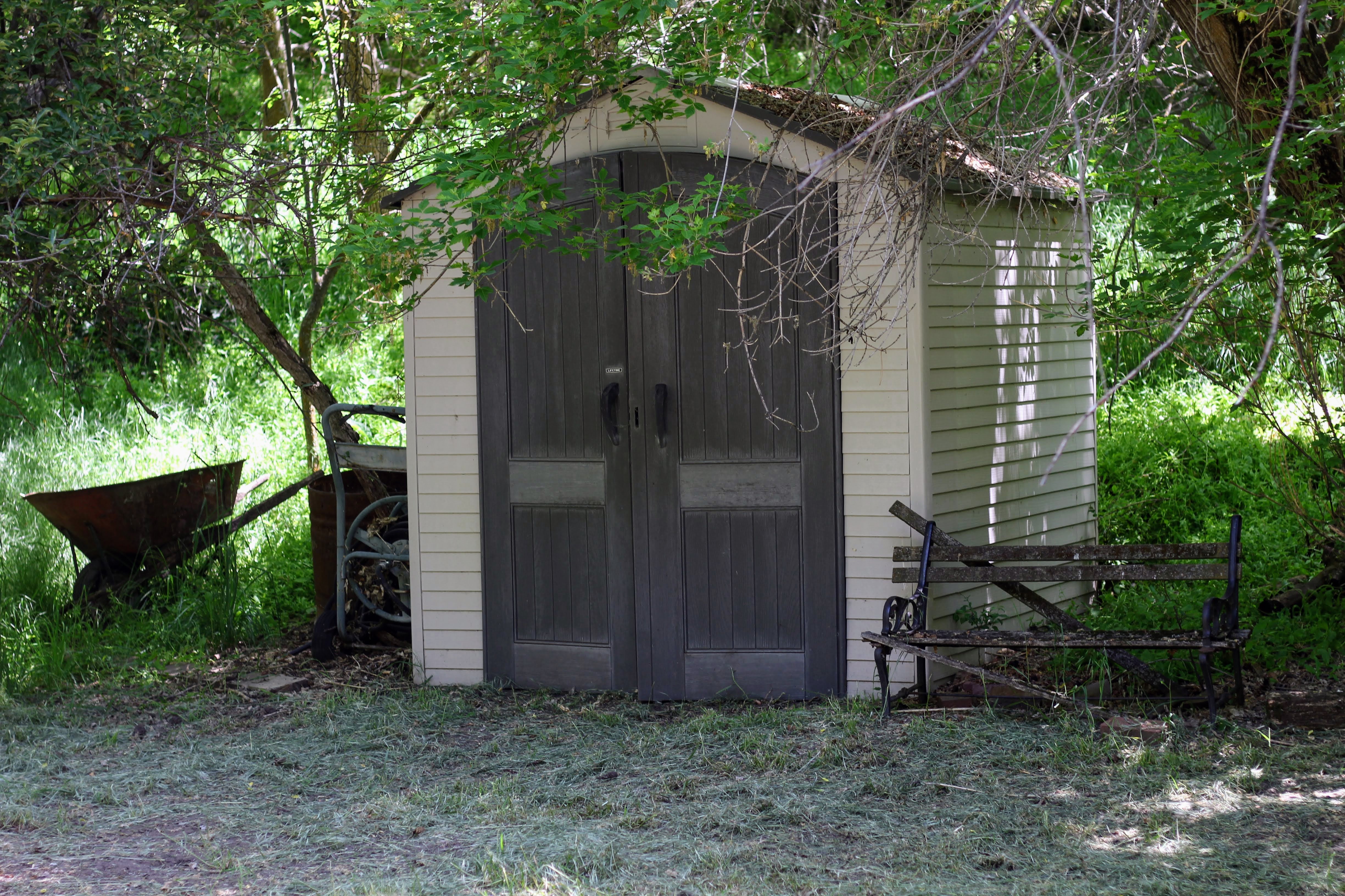 Detached storage shed featuring vertical panel doors, horizontal siding, and a sloped roofline