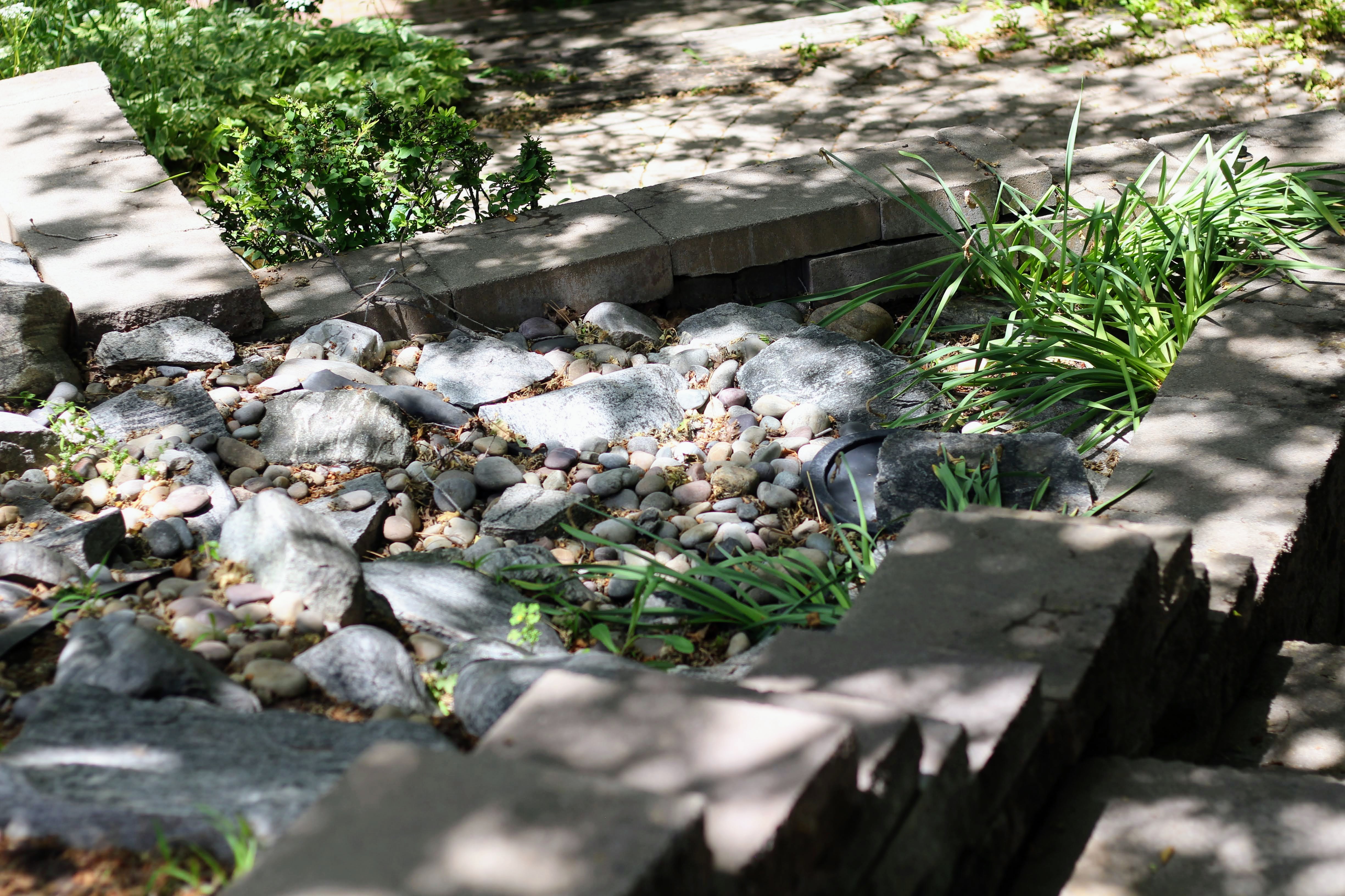 Tiered garden bed featuring a mix of natural stones and pebbles, complemented by green plantings