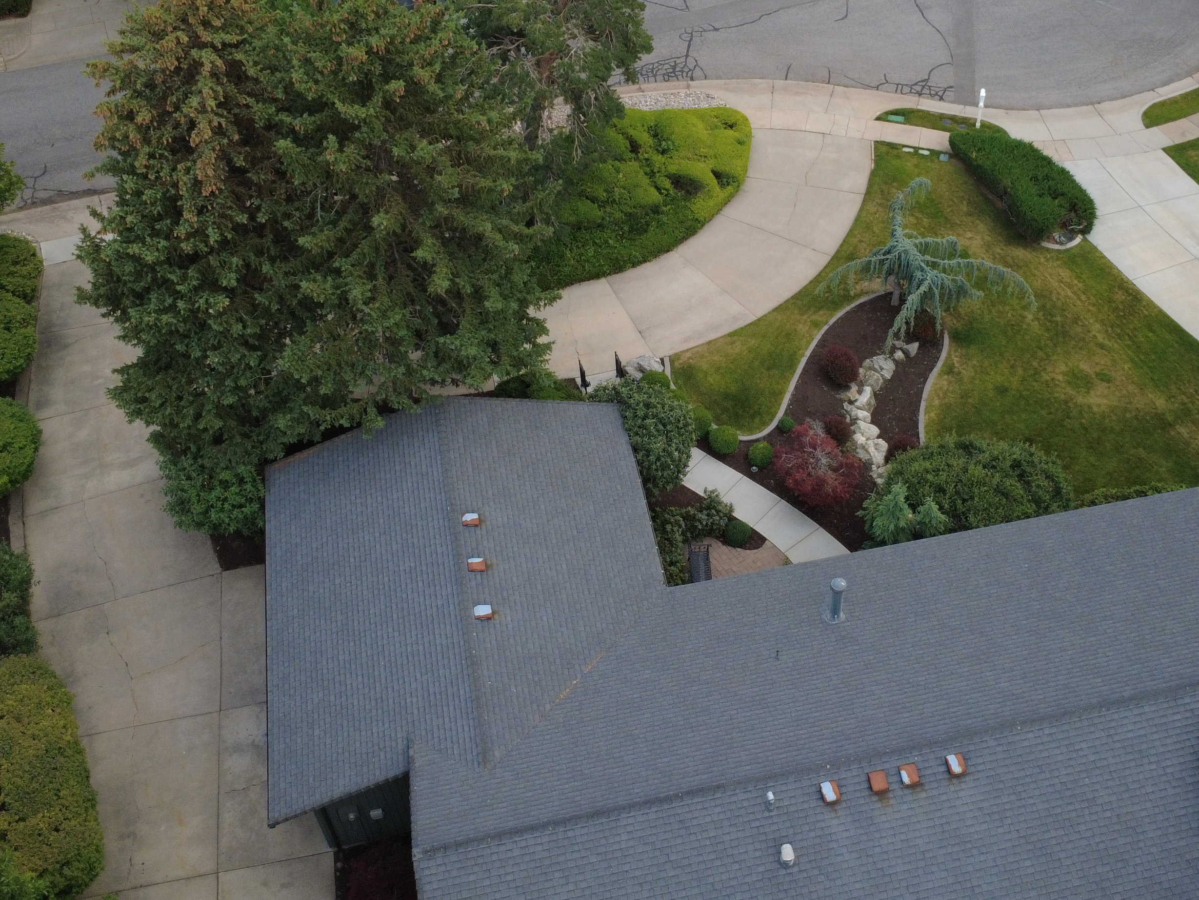 Property situated on a cul-de-sac, featuring a dark gray shingle roof and a stone-clad chimney
