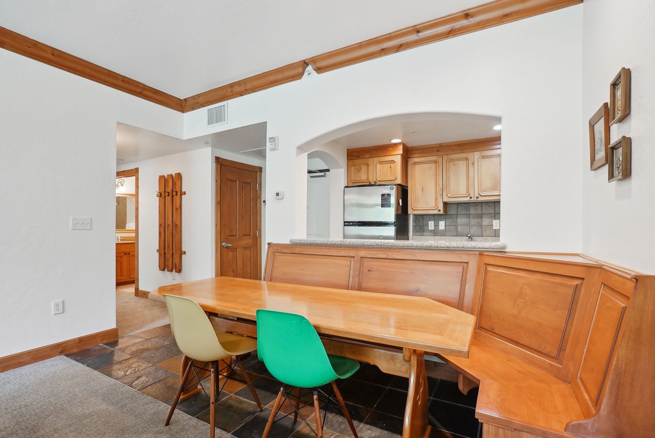 Built-in corner banquette seating with wood-finish table, tile flooring, and wood beam ceiling accents