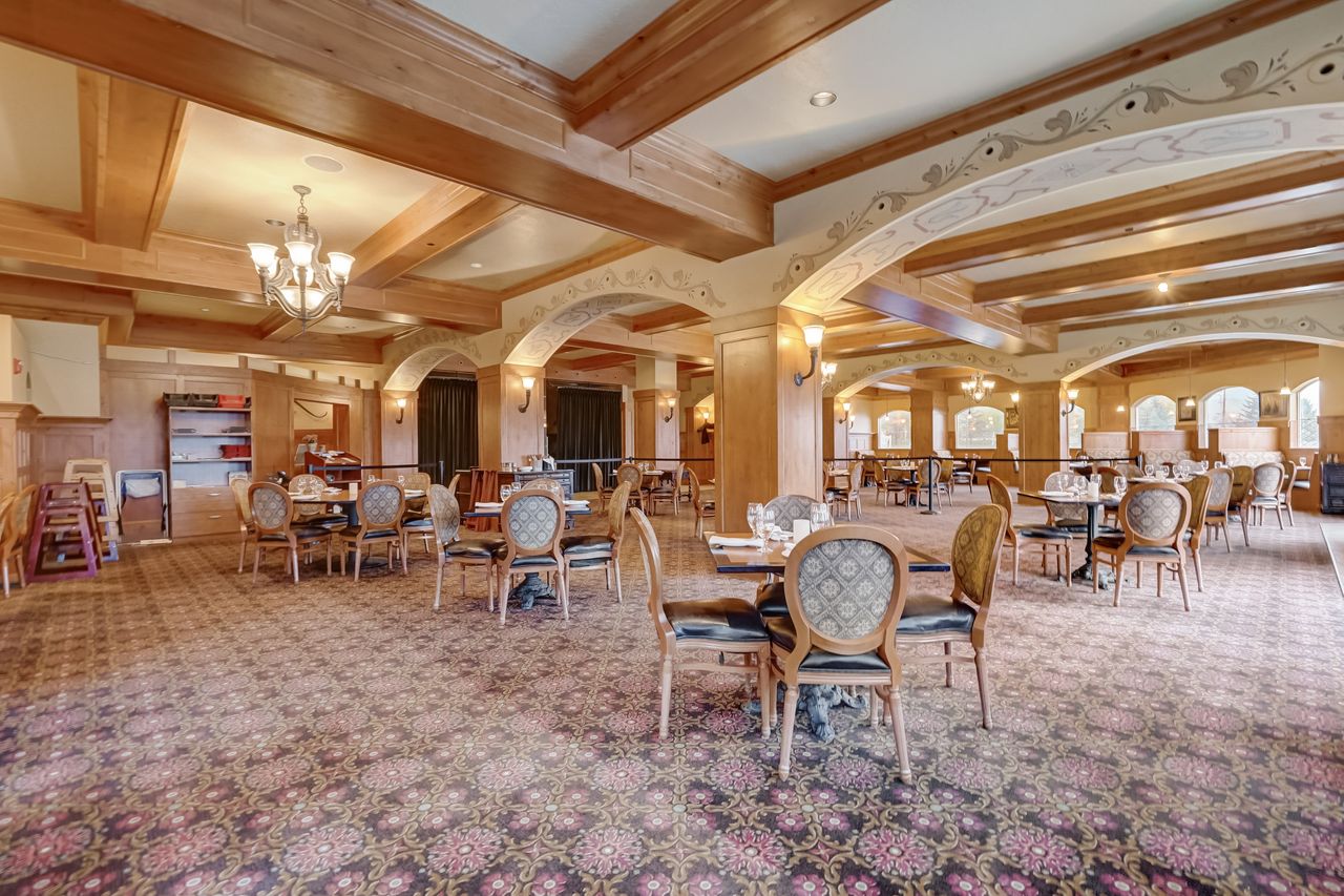 Spacious interior featuring exposed wooden beams, patterned carpeting, and decorative wall sconces