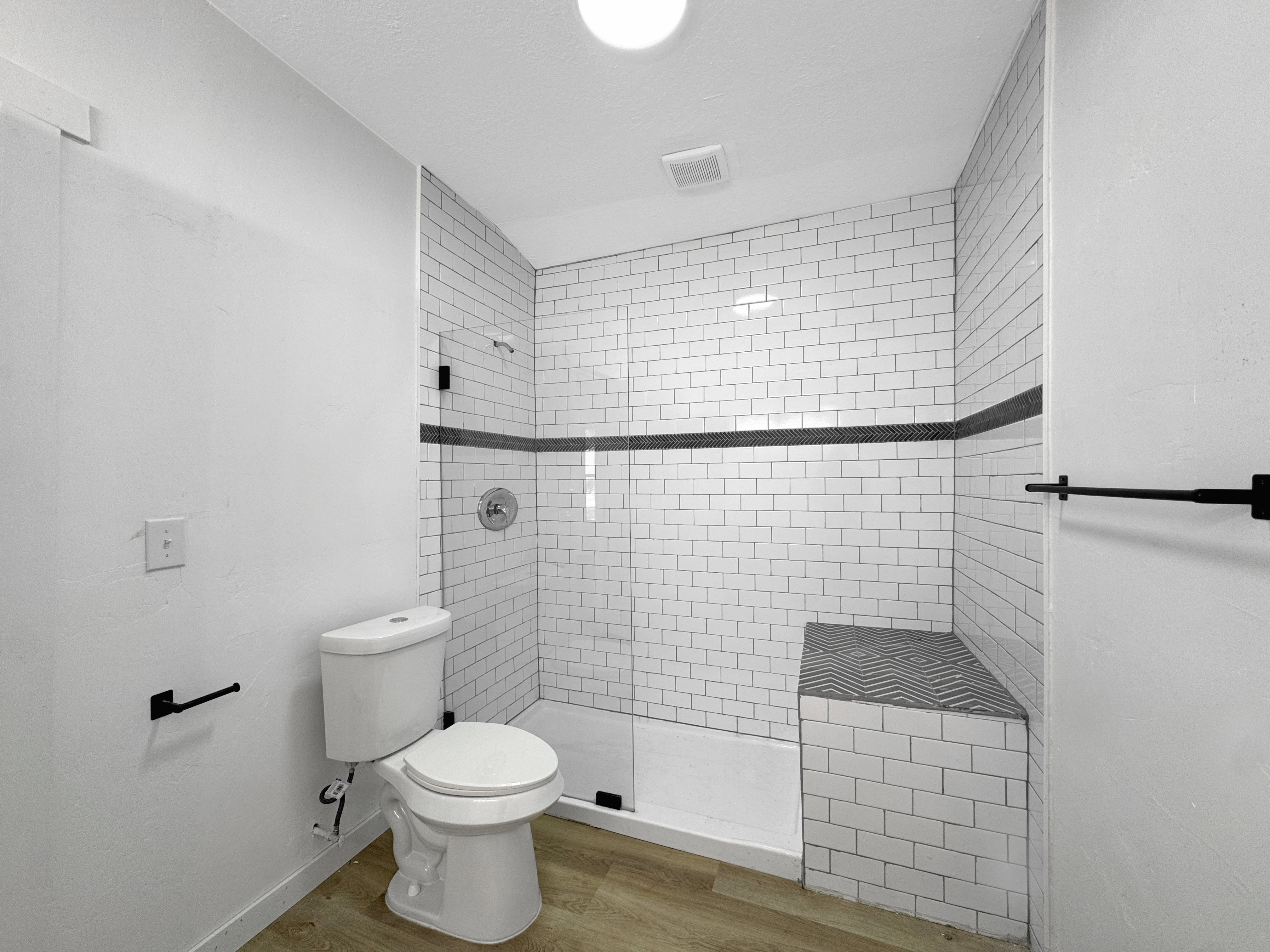 Shower enclosure featuring subway tile surround with a decorative accent band and integrated bench seating