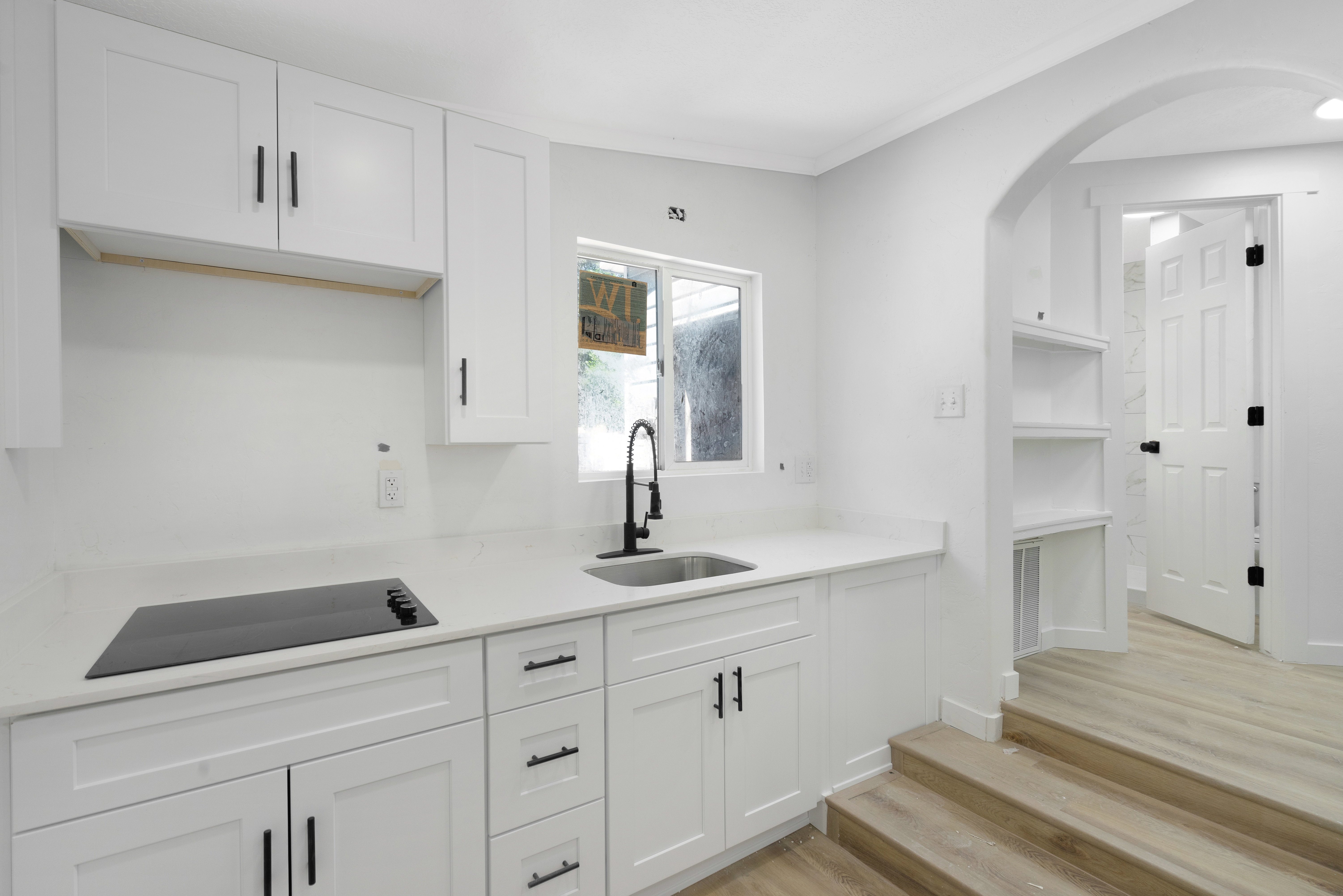 Additional kitchen. Contemporary white kitchen with quartz countertops, integrated cooktop, undermount sink, and matte black fixtures