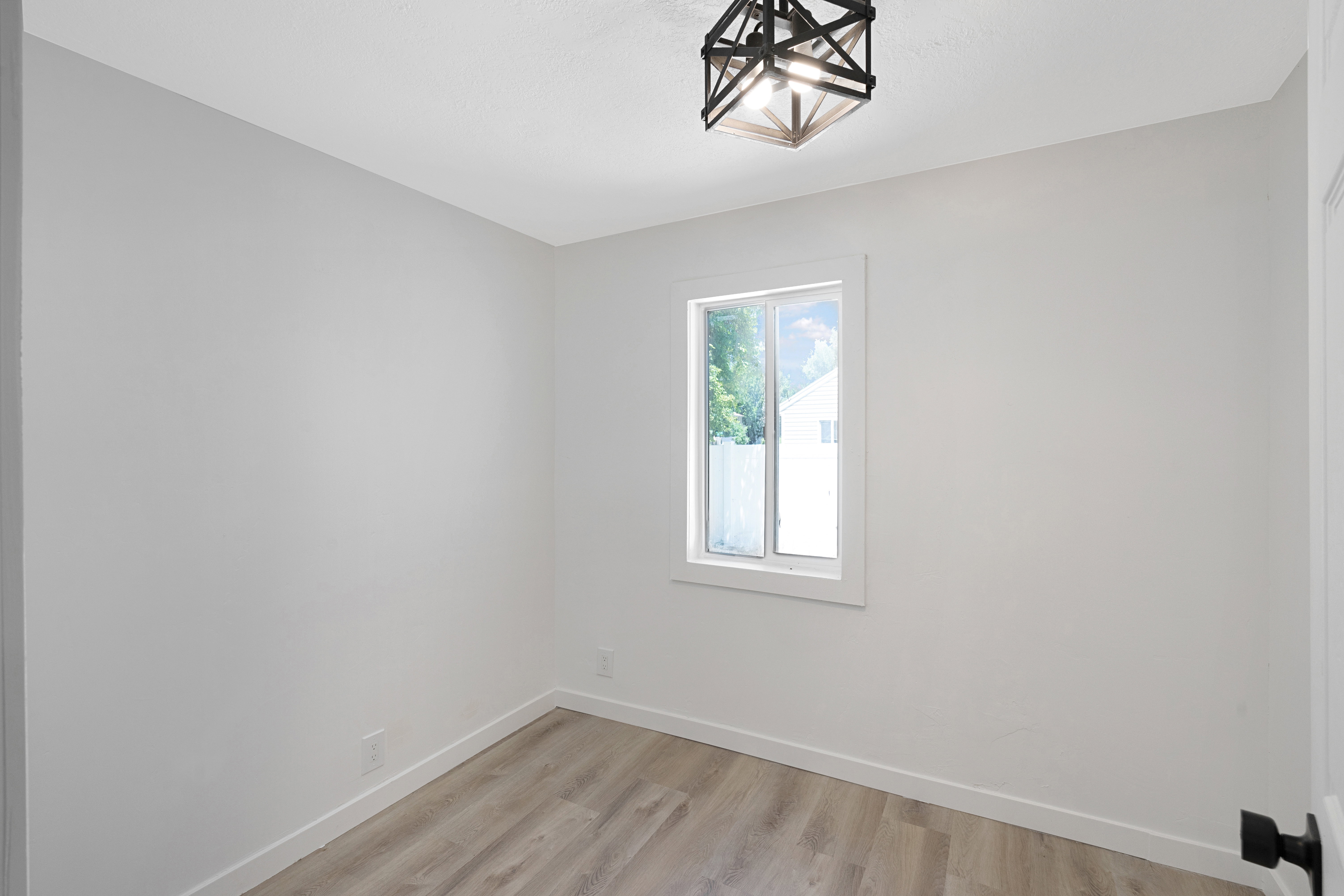 Interior room featuring a single window, overhead semi-flush mount lighting, light wood-finish flooring, white baseboards, and neutral wall paint