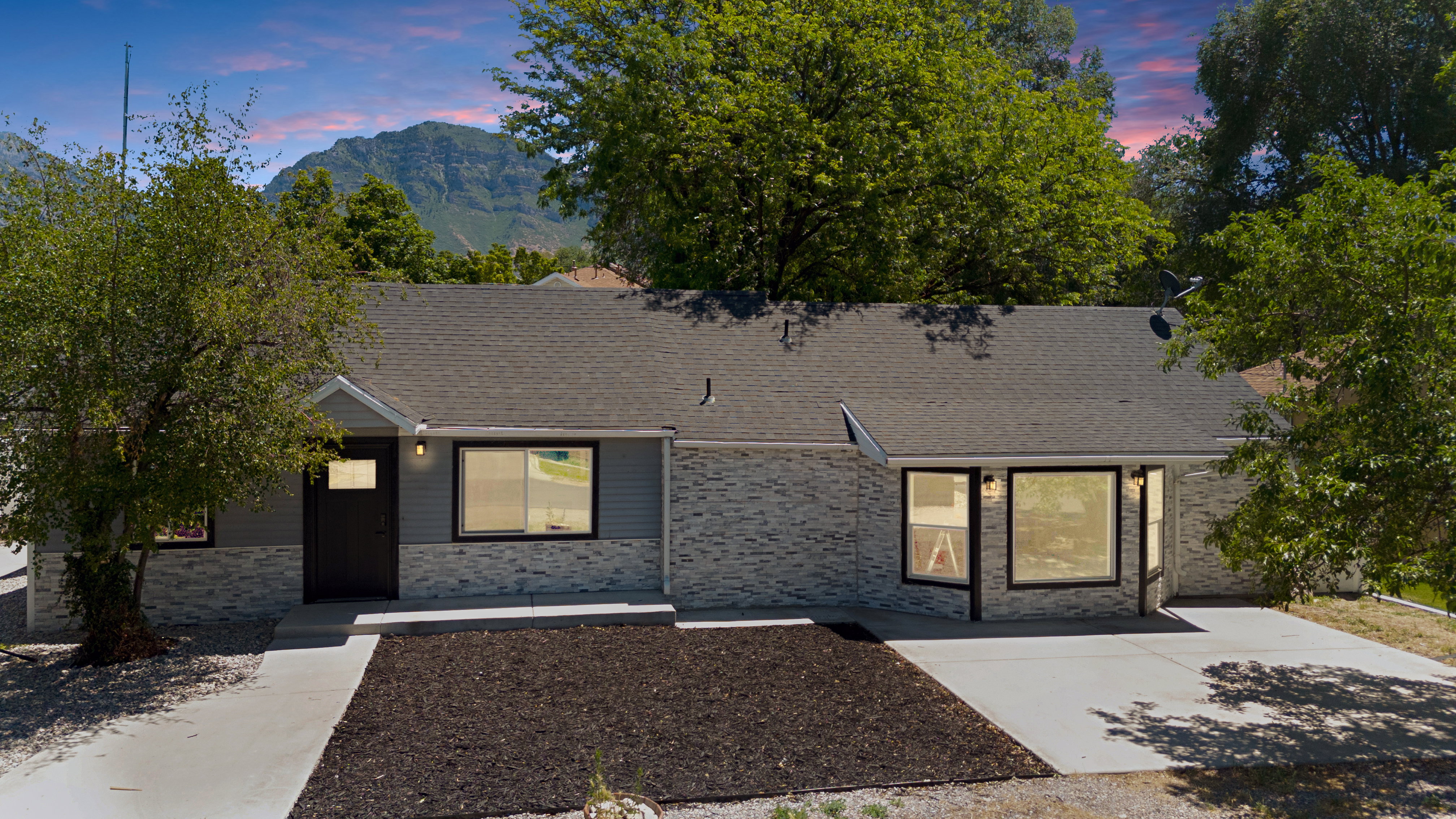 Single-story residence featuring a dark asphalt shingle roof and a light gray brick facade