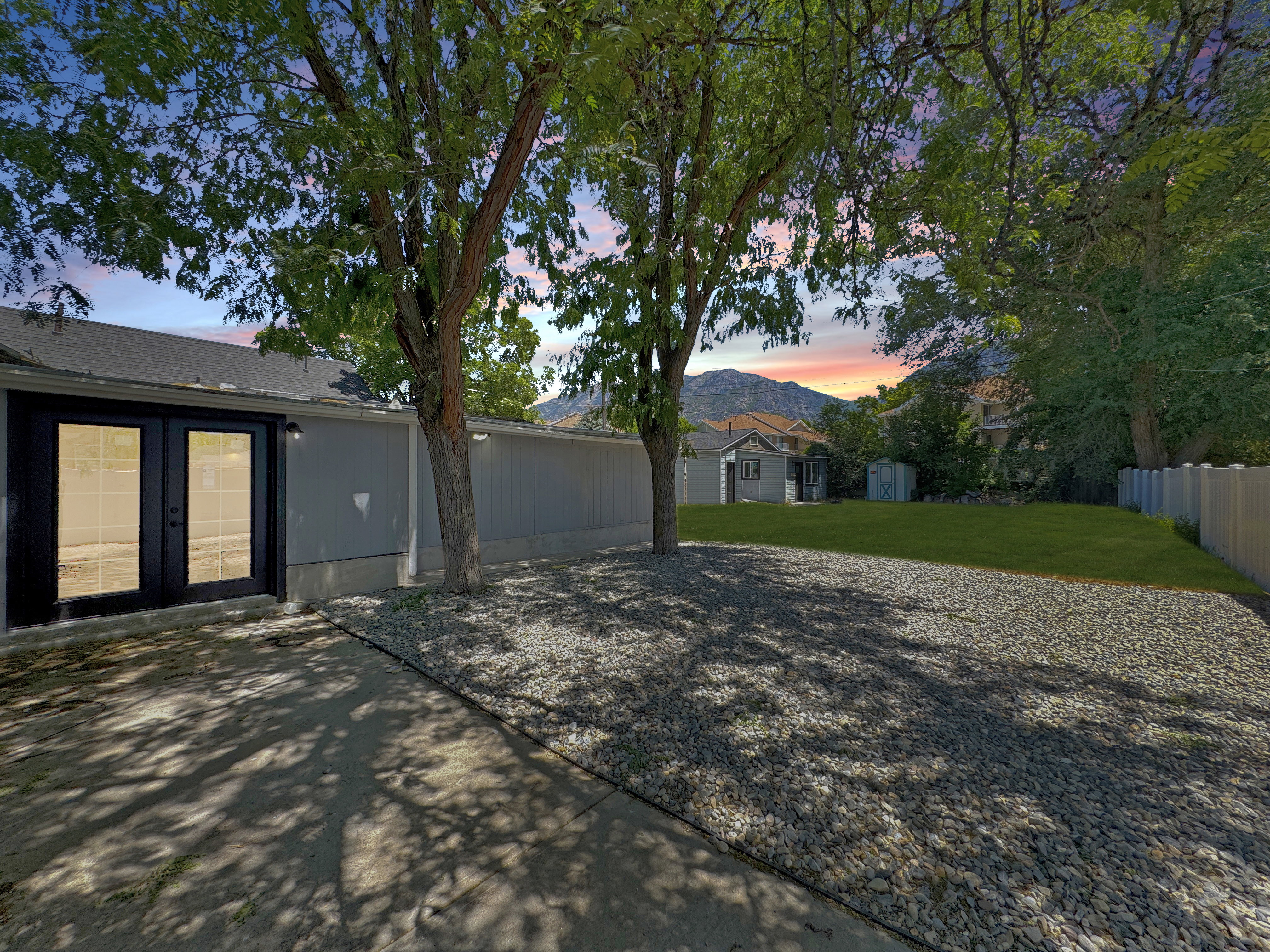 Backyard featuring a concrete patio, gravel area, and a grassy expanse