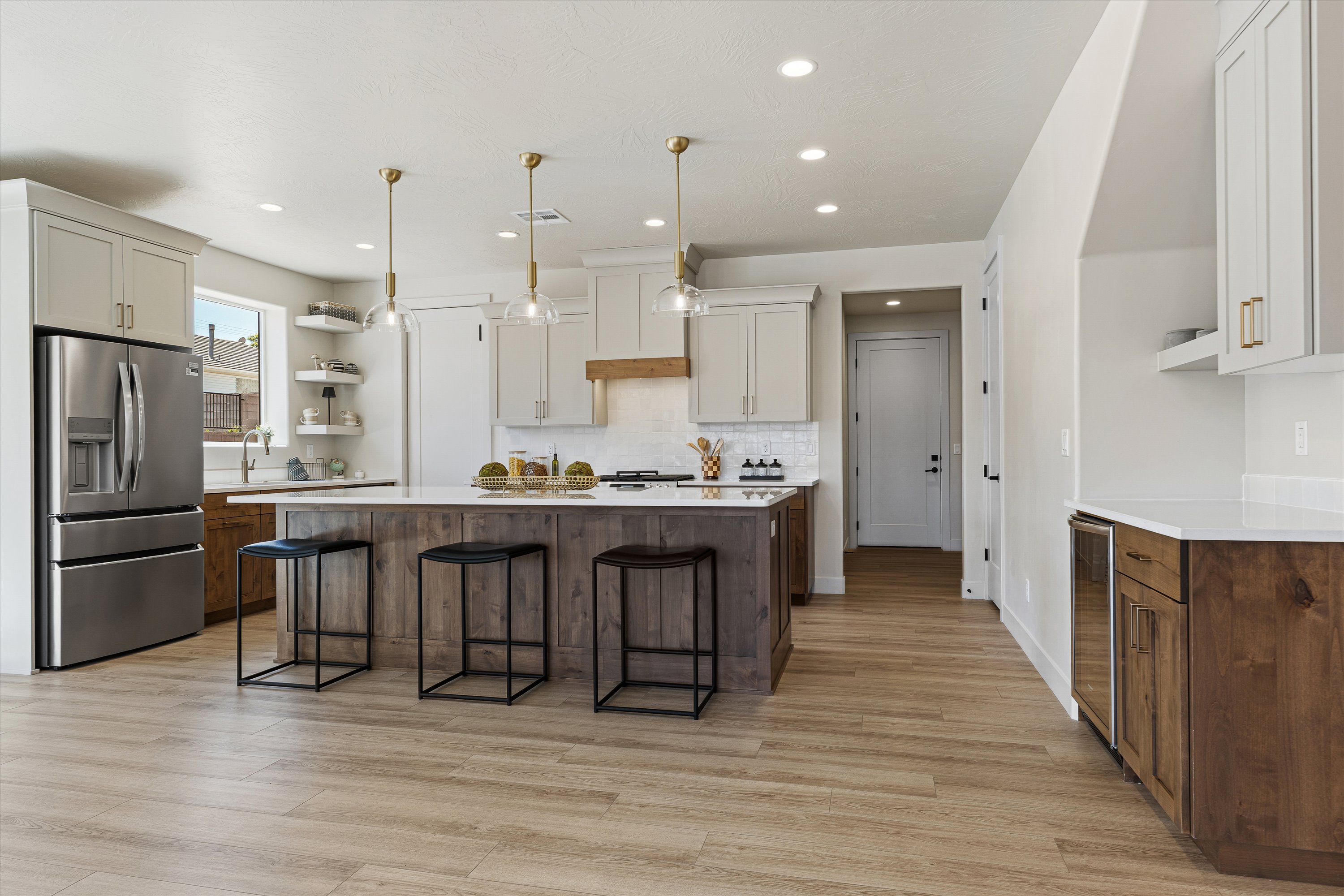 Spacious kitchen featuring a central island with counter seating, light wood-finish flooring, white countertops, built-in shelving, and stainless steel appliances