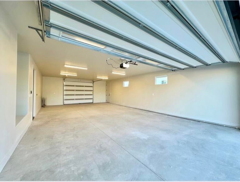 Spacious garage featuring a concrete floor, two overhead garage doors, multiple windows, and recessed lighting fixtures