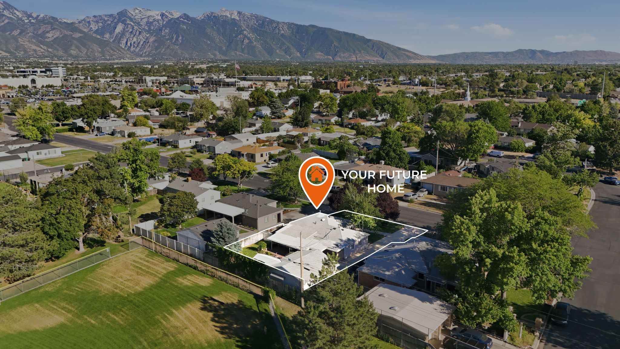 Aerial perspective highlighting a single-story residence with a white roof in a neighborhood setting, framed by mature trees and mountain scenery