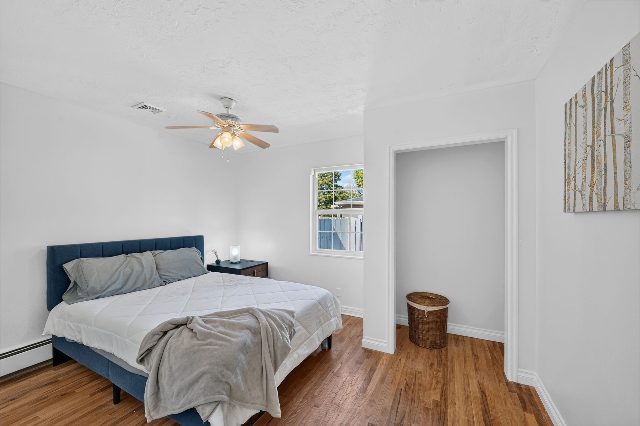 Bedroom featuring wood-finish flooring, white walls, and a ceiling fan with integrated lighting