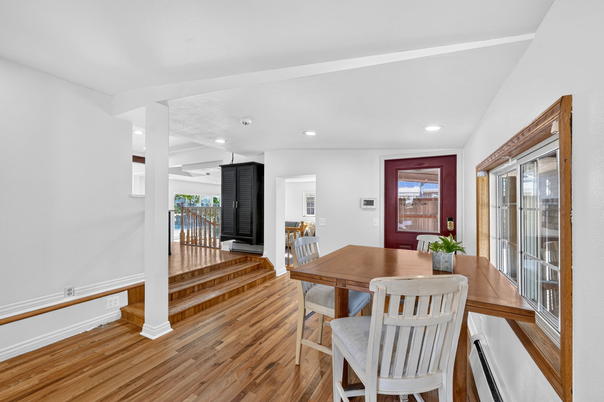 Hardwood flooring throughout, recessed lighting, white trim, and a red entry door