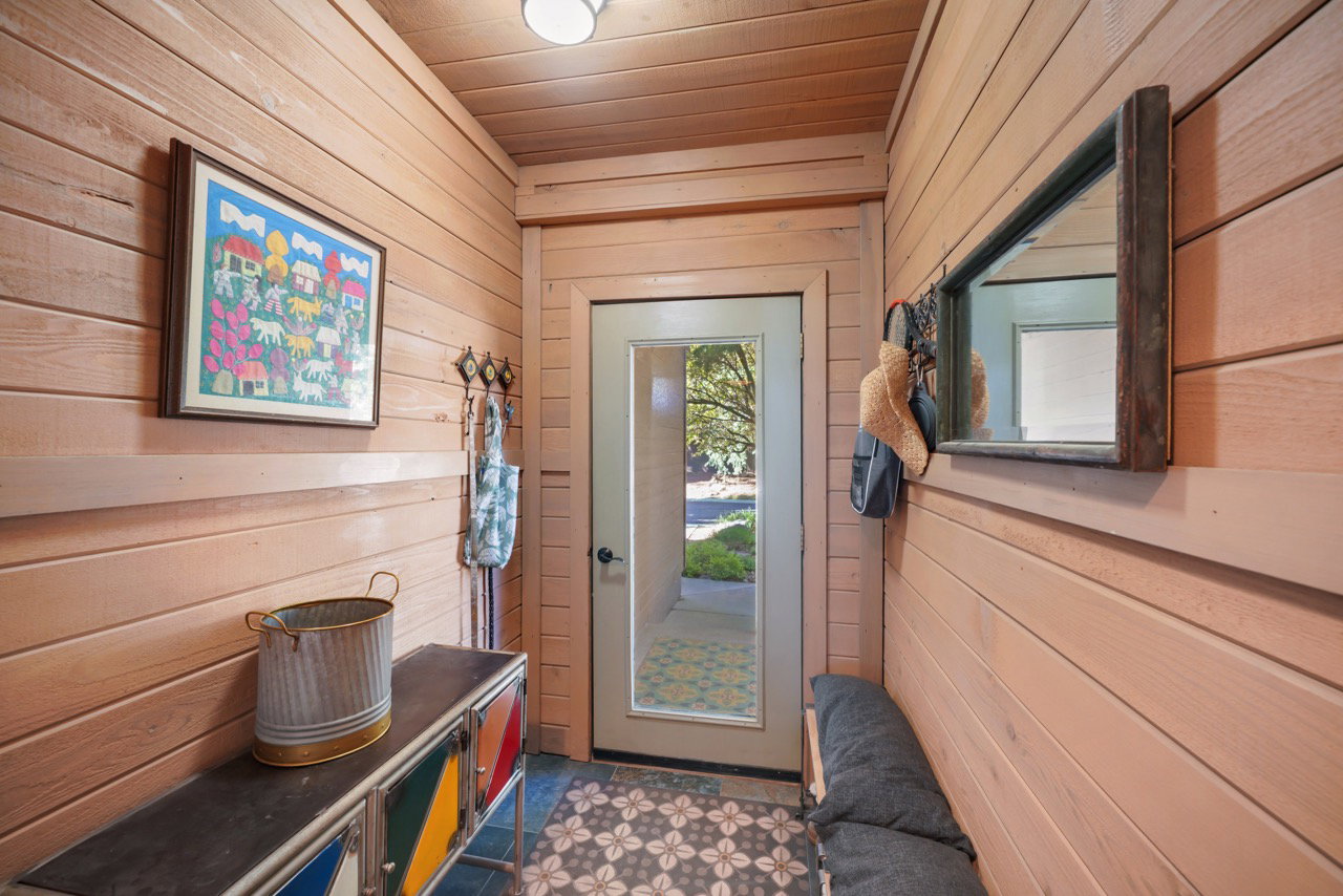 Entryway featuring horizontal wood paneling, a recessed light fixture, a glass-paneled door, and patterned floor tiling