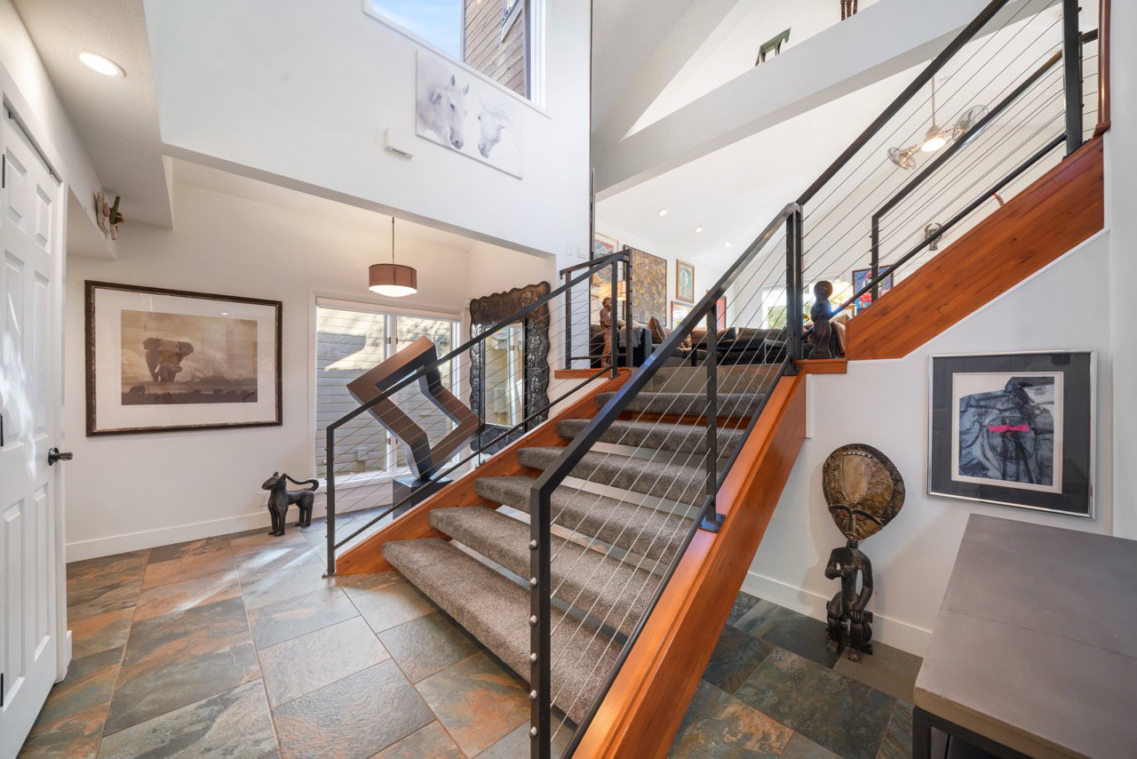 Staircase with cable railing system and wood-finish handrail, featuring carpeted treads