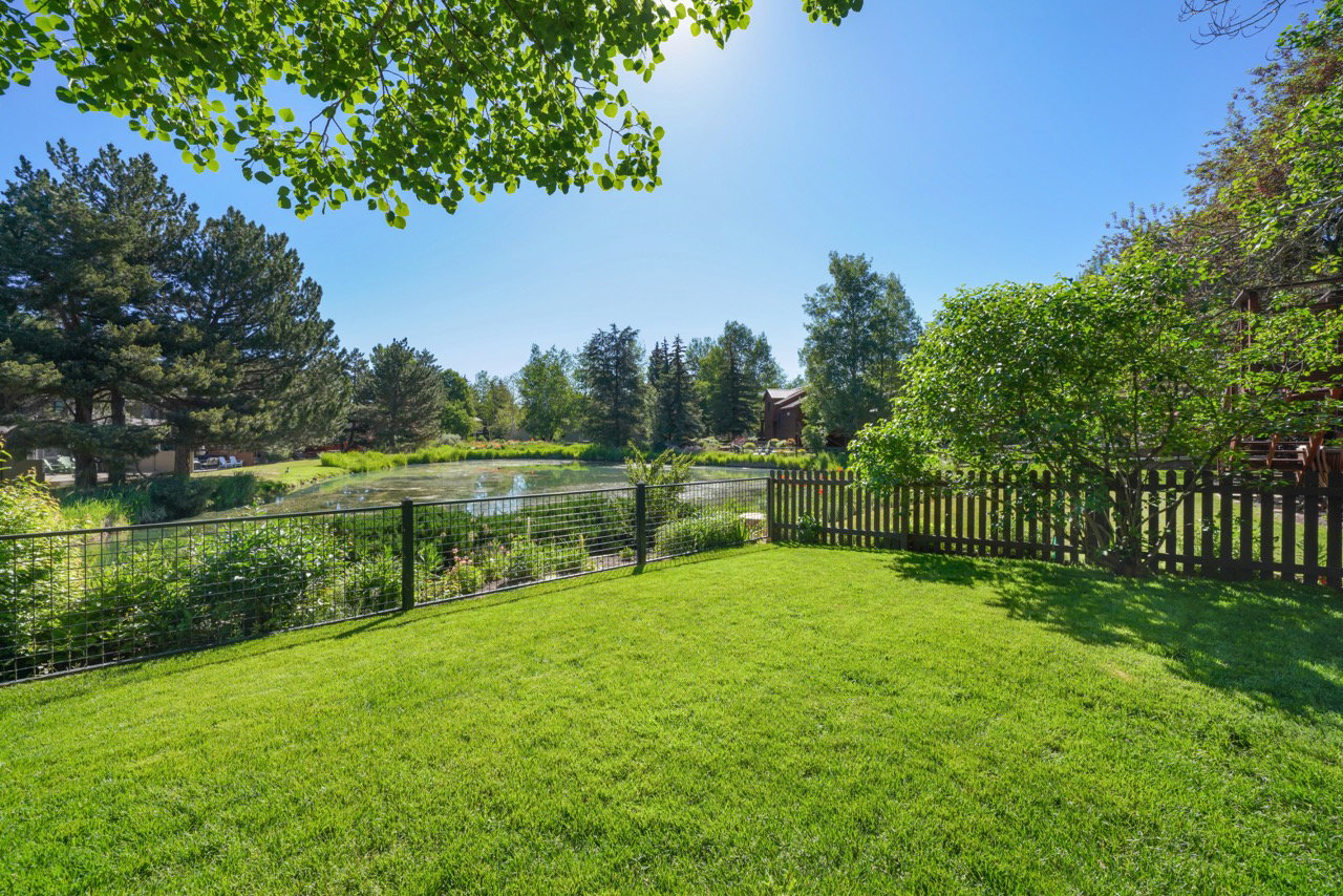 Expansive green lawn with a dark wood picket fence and a metal wire fence
