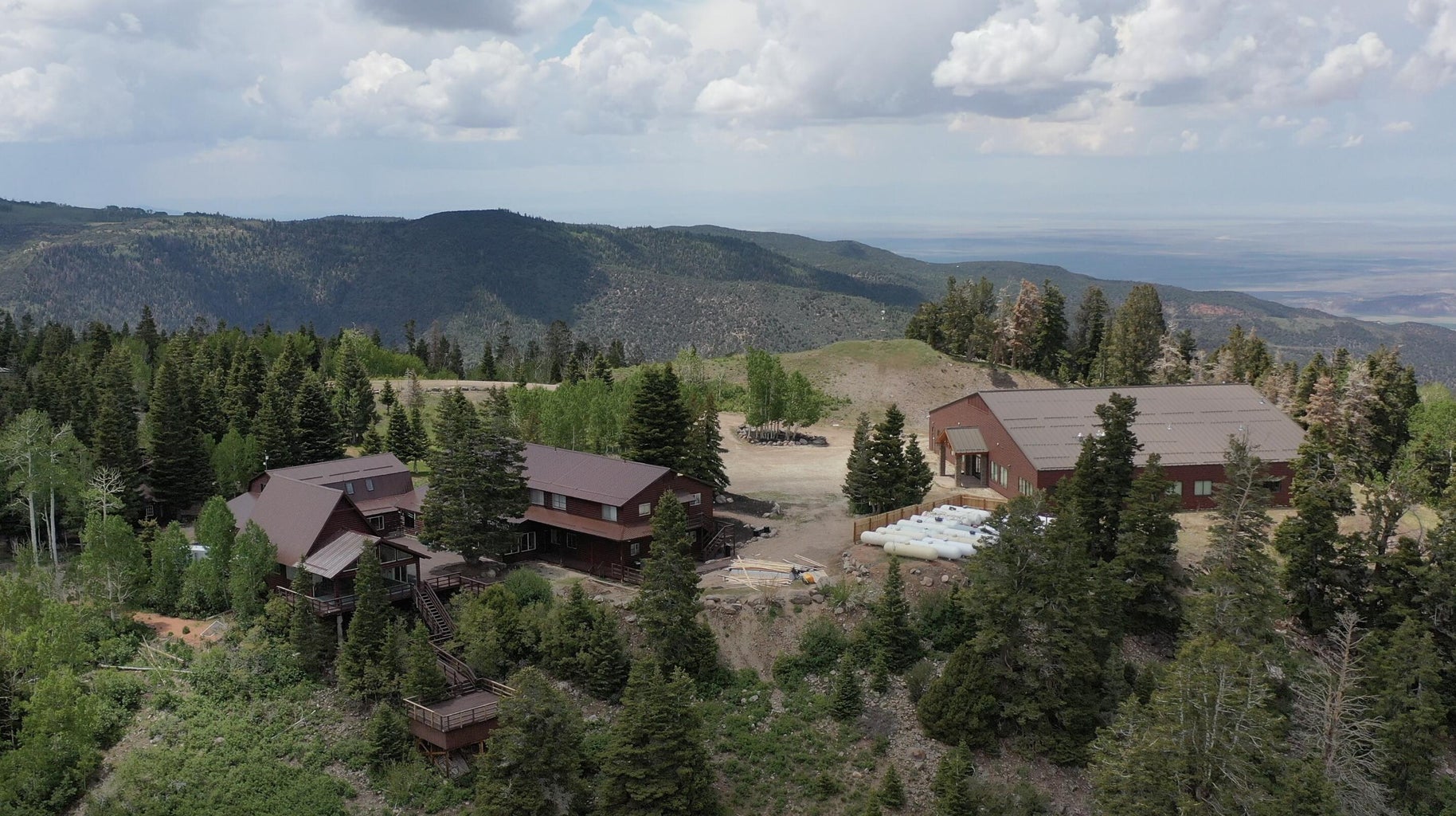 Mountain property featuring multiple structures, including two multi-story buildings with brown exteriors and dark roofs