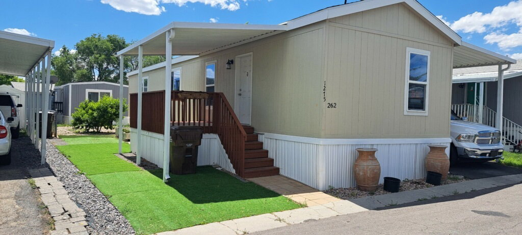 Manufactured home featuring covered entry, exterior stairs, and a covered parking area