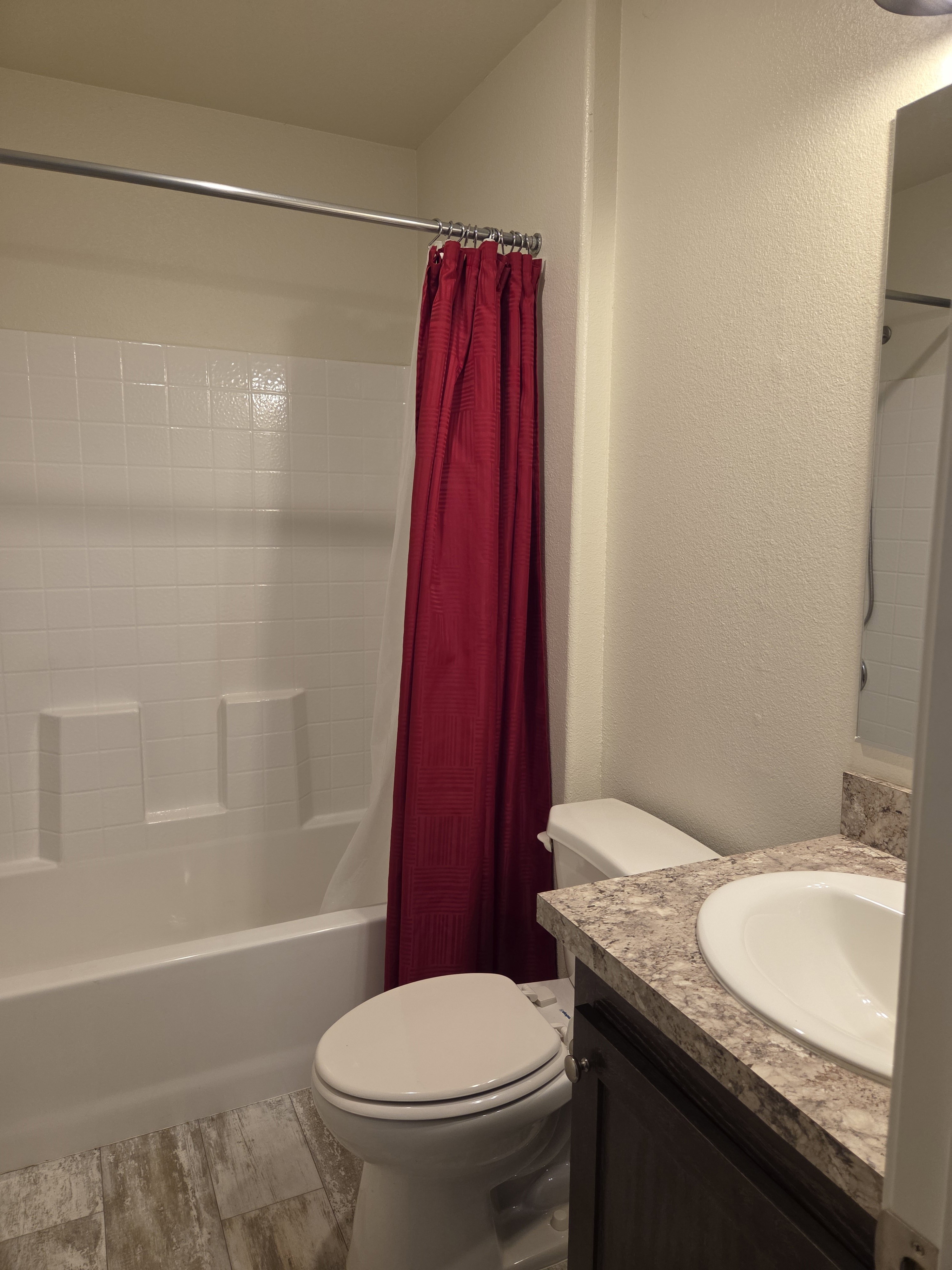Bathroom featuring a white tub and shower surround, a white toilet, and a vanity