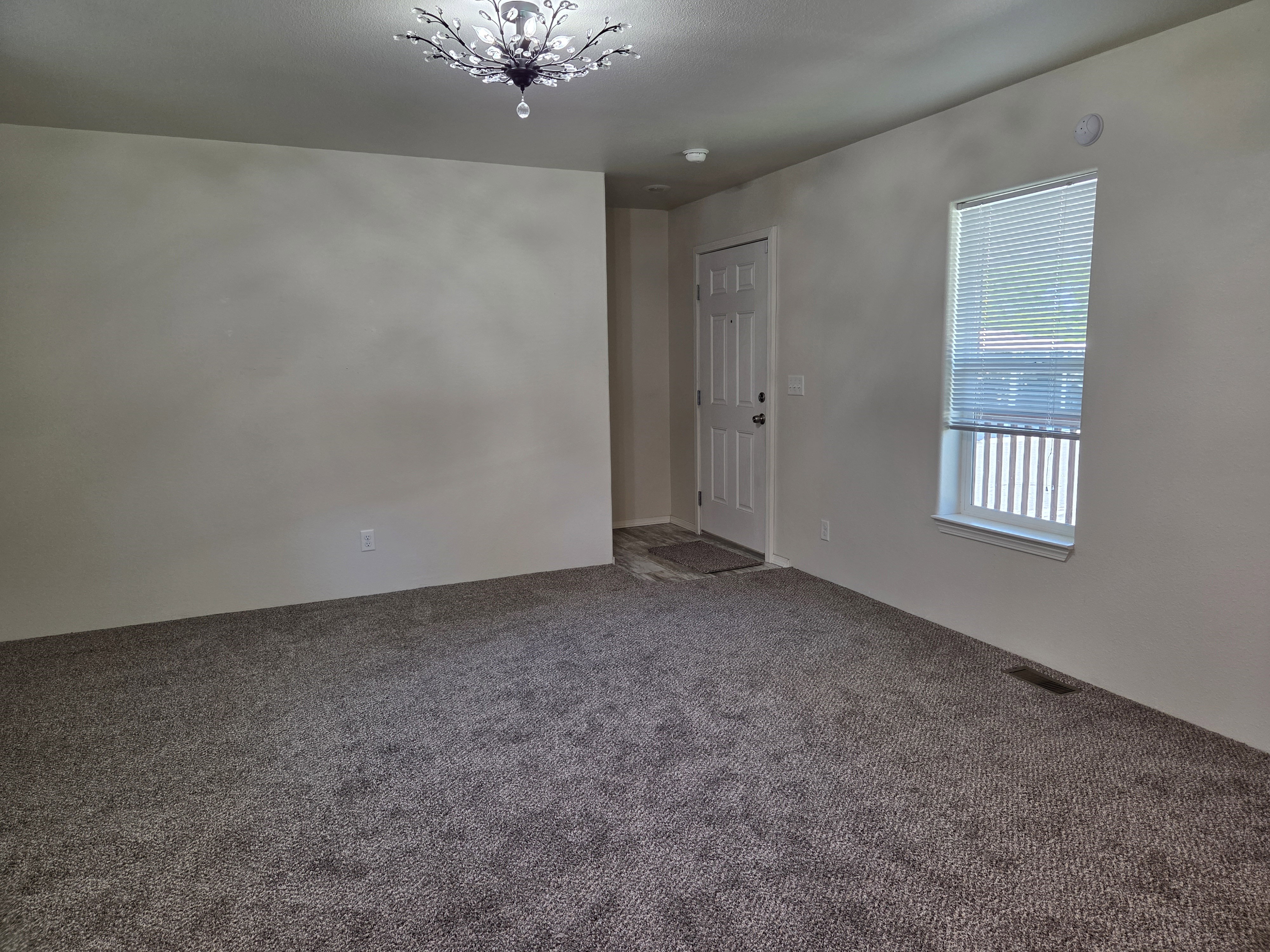Neutral-toned carpet flooring, light wall paint, and a decorative ceiling light fixture