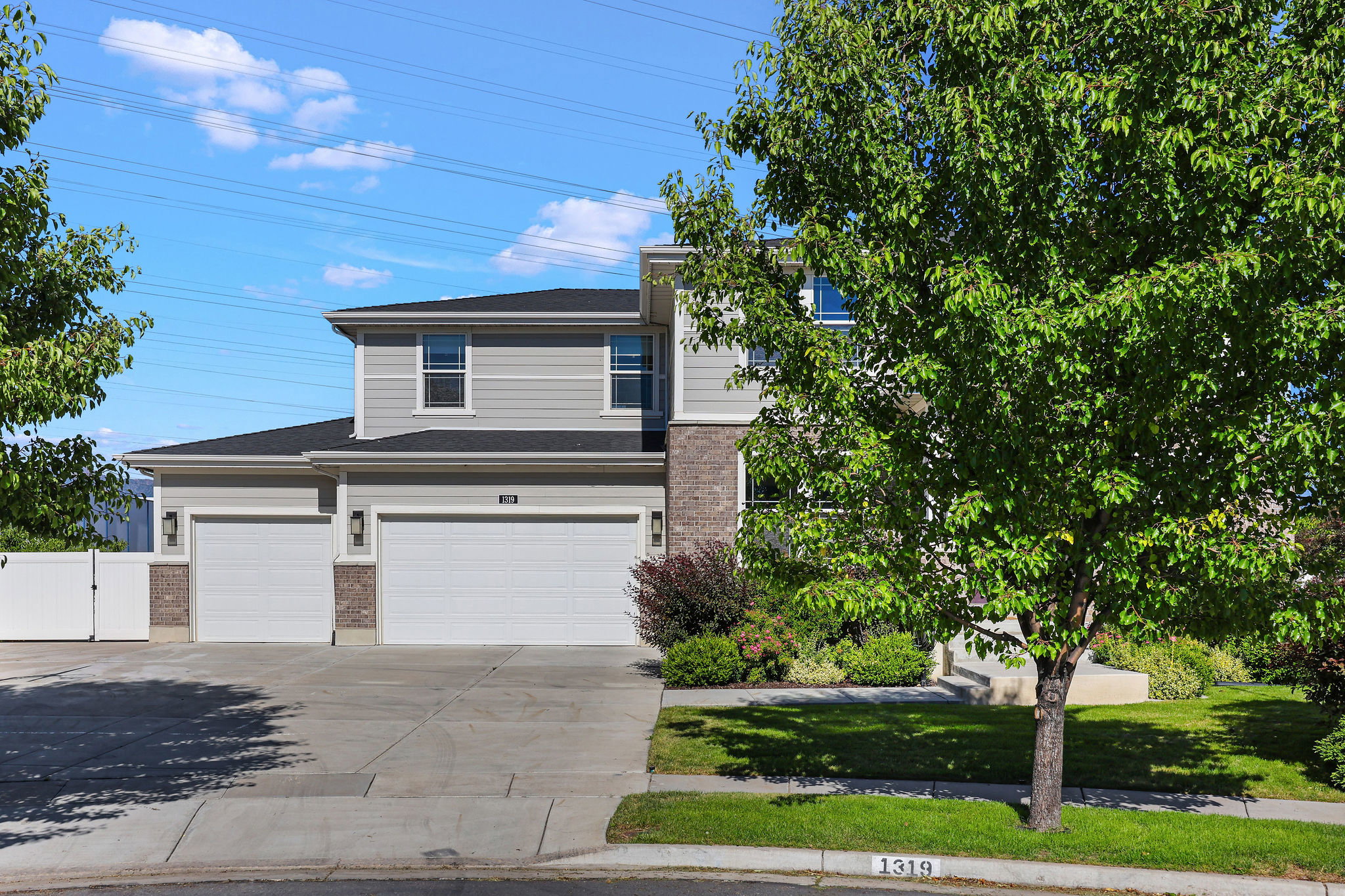 Contemporary two-story residence featuring light gray siding and brick accents