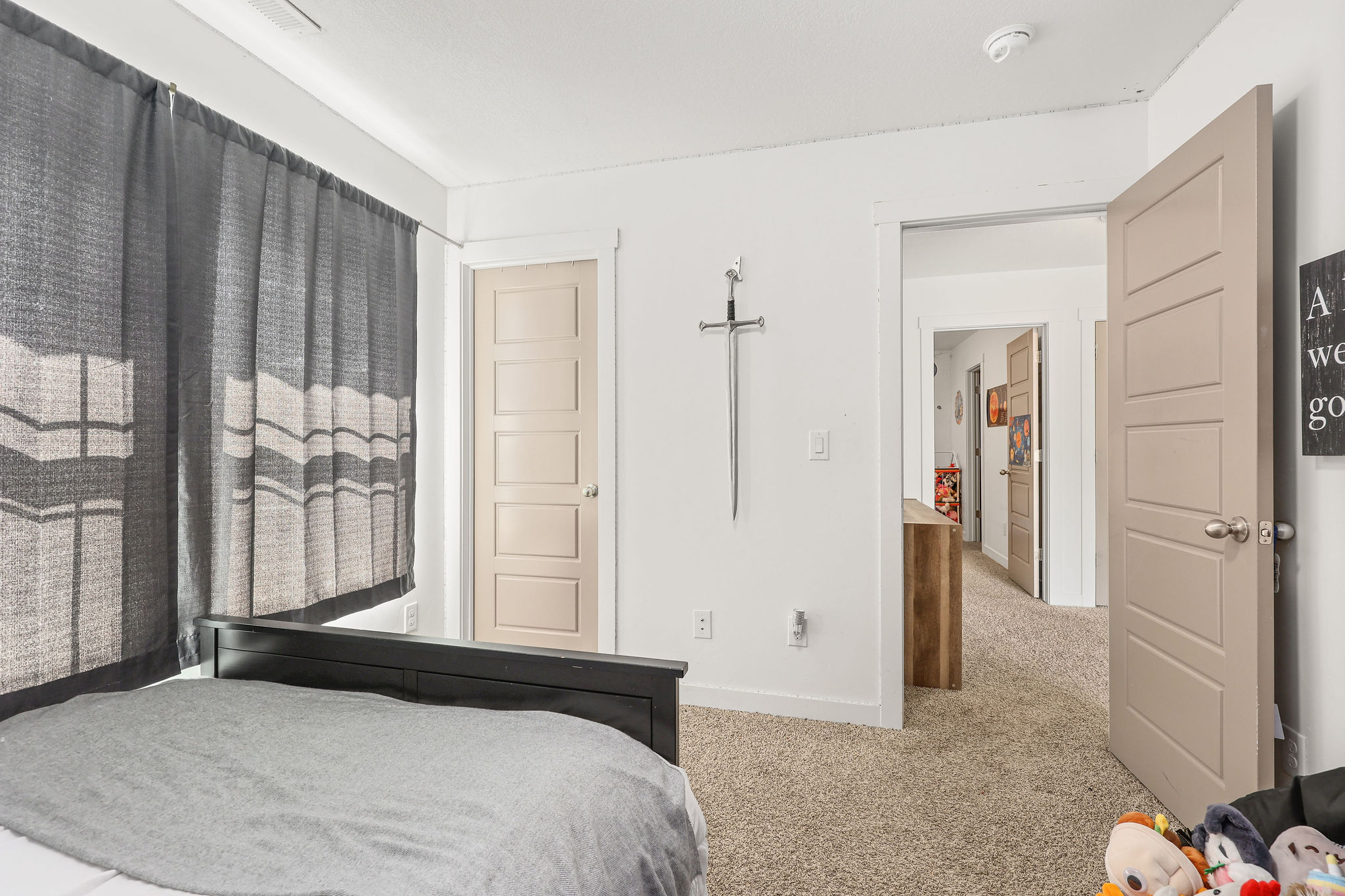 Neutral-toned bedroom featuring a dark-paneled bed frame and wall-to-wall carpeting