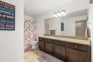 Full bathroom featuring a dark wood-finish vanity with a light-colored countertop, a single sink, and a large wall-mounted mirror