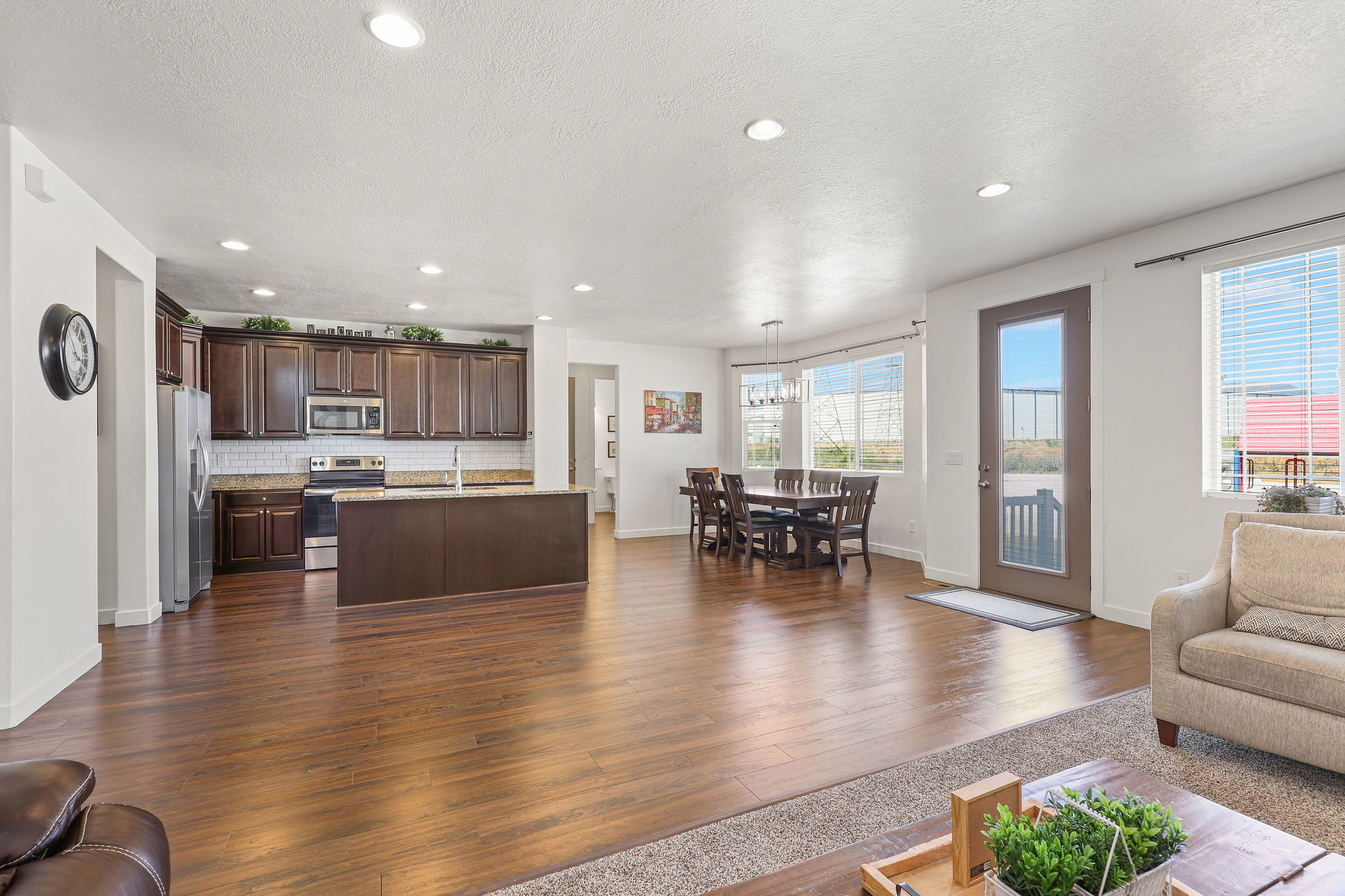 Open-concept floorplan featuring wood-finish flooring, recessed lighting, and a kitchen with dark wood cabinetry