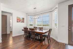 Dining area featuring wood-finish flooring, a contemporary linear chandelier, multiple windows with horizontal blinds, and a neutral color palette