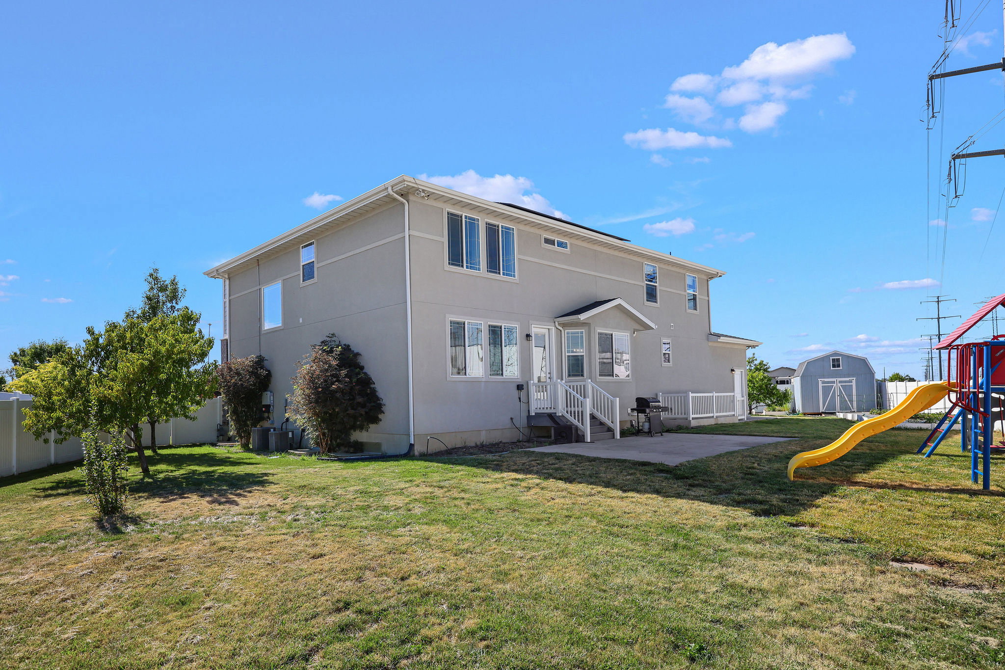 Rear exterior featuring stucco siding, a ground-level concrete patio, and a white deck with railings