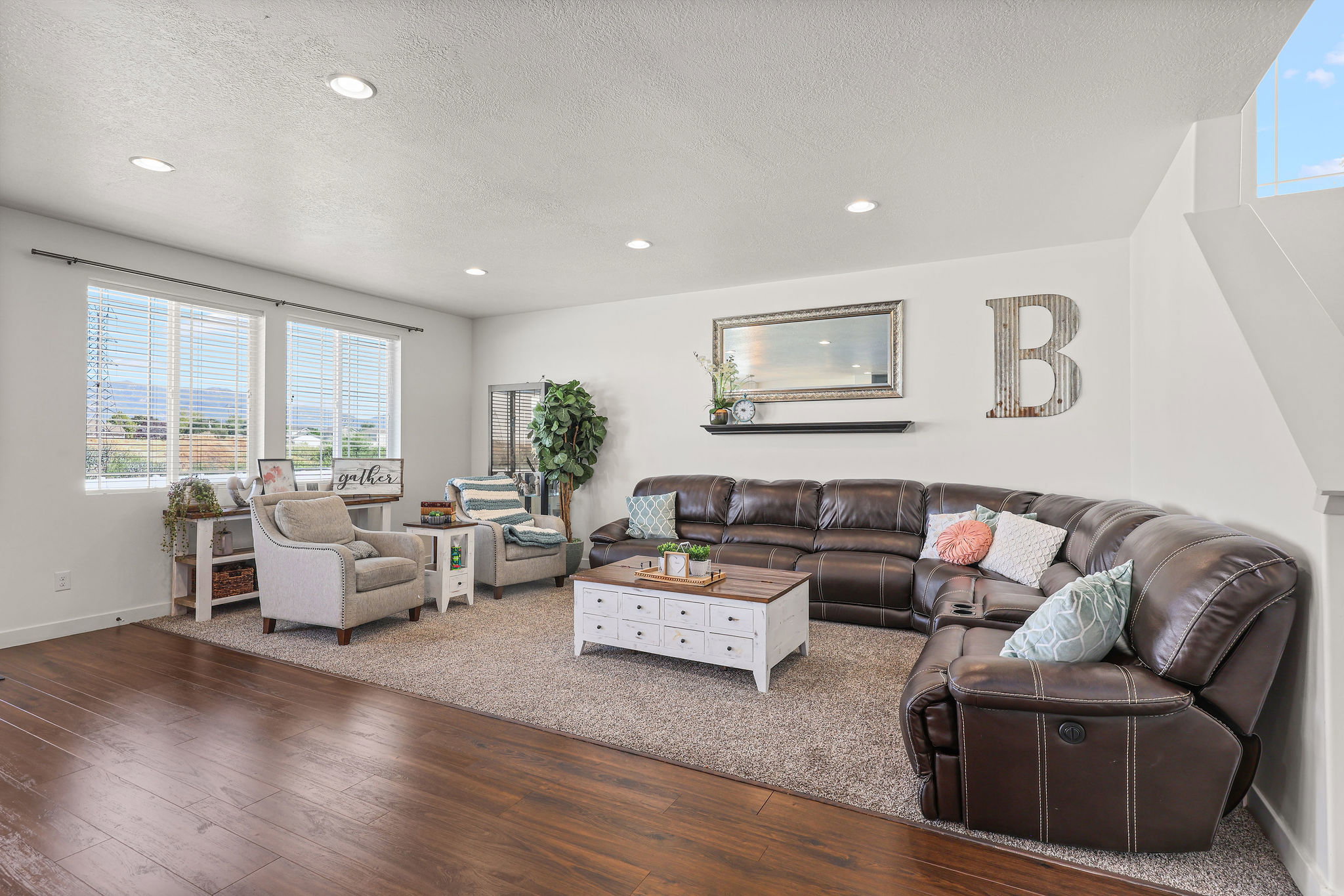 Spacious living area featuring recessed lighting, a large window array, and wood-finish flooring transitioning to an area rug