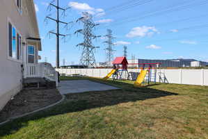 Expansive backyard featuring a concrete patio, a manicured lawn, and white vinyl fencing